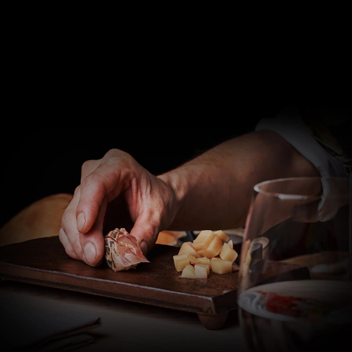 Fine dining chef plating artisanal cured salmon and cheese on a wooden board in a professional kitchen.