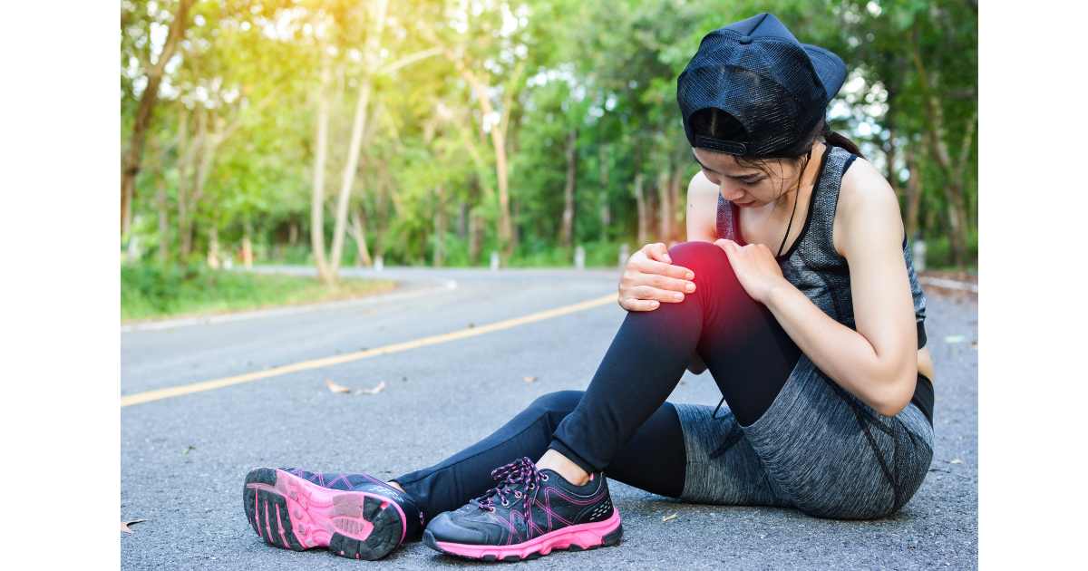 Female runner sitting on the road, holding her knee in pain after a high-impact workout, highlighting the need for joint-friendly exercise solutions like Kangoo Jumps. Female runner sitting on the road, holding her knee in pain after a high-impact workout, highlighting the need for joint-friendly exercise solutions like Kangoo Jumps.