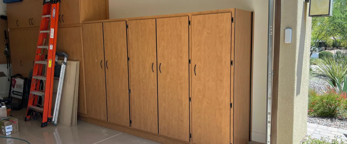 Installed wood garage cabinets with ladder and tools nearby