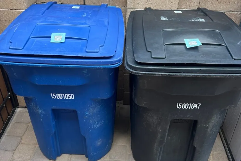 Side-by-side blue and black trash bins with QR codes on the lids Side-by-side blue and black trash bins with QR codes on the lids