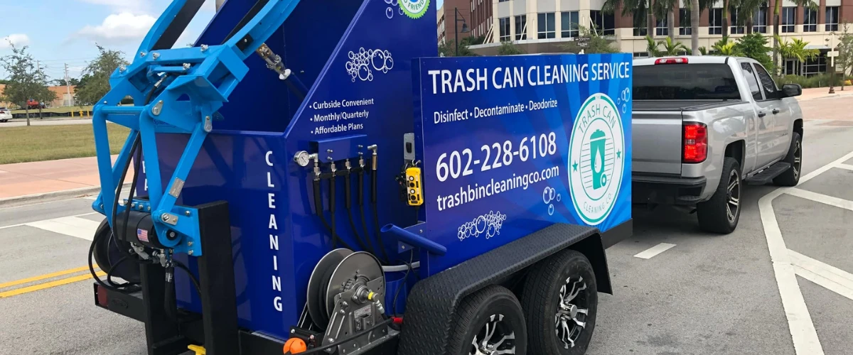 Trash can cleaning trailer attached to truck with service branding and equipment. Trash can cleaning trailer attached to truck with service branding and equipment.