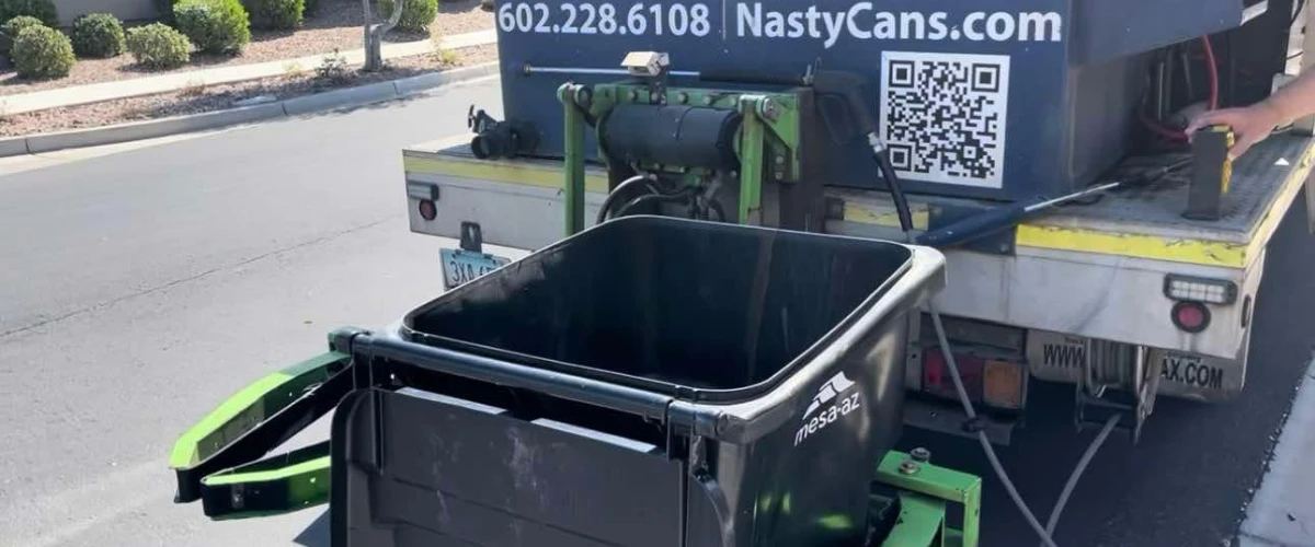 Trash can cleaning truck lifting a residential garbage bin using hydraulic arms. Trash can cleaning truck lifting a residential garbage bin using hydraulic arms.