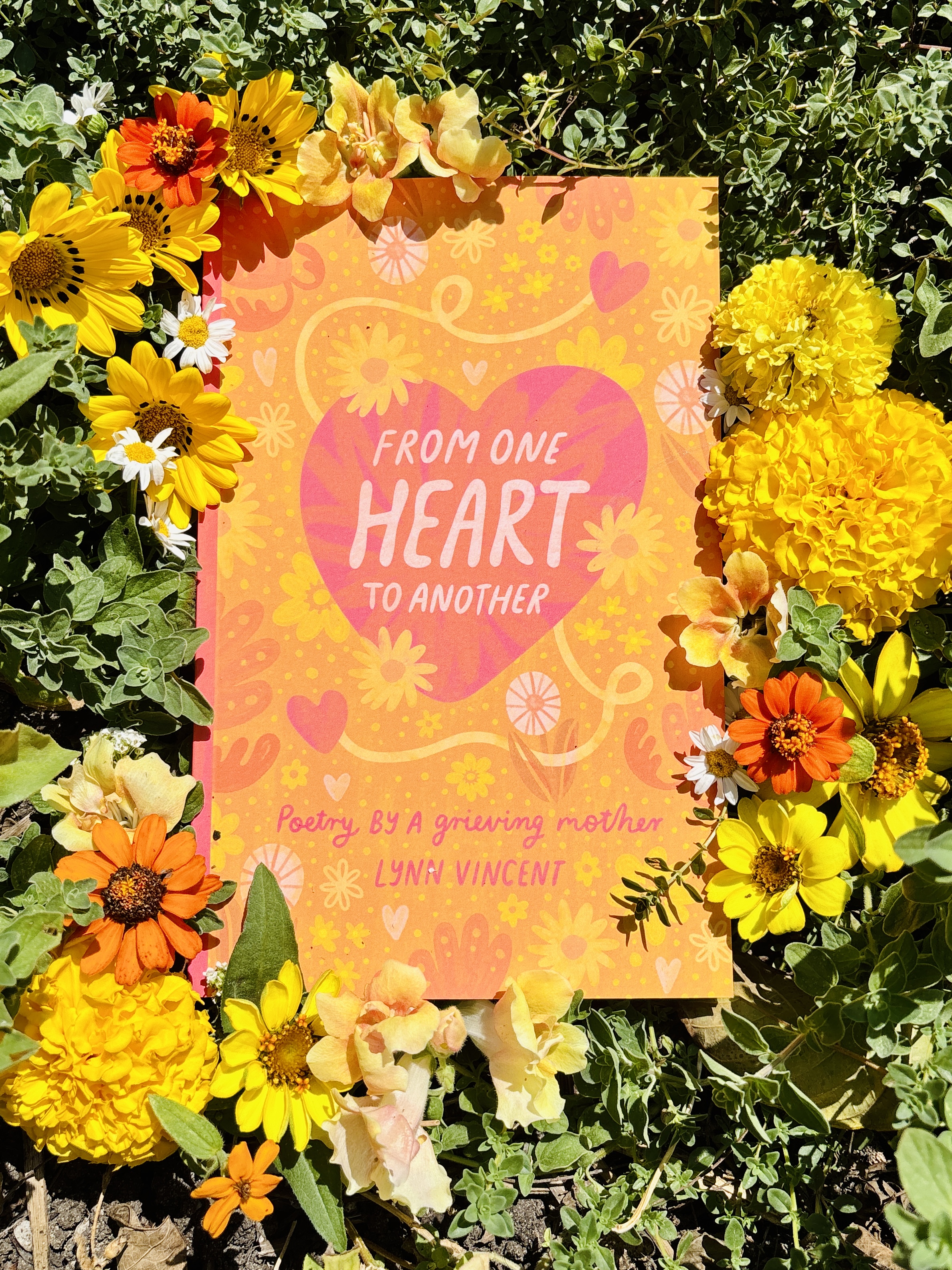 'From One Heart To Another:Poetry By A Grieving Mother' book surrounded by flowers
