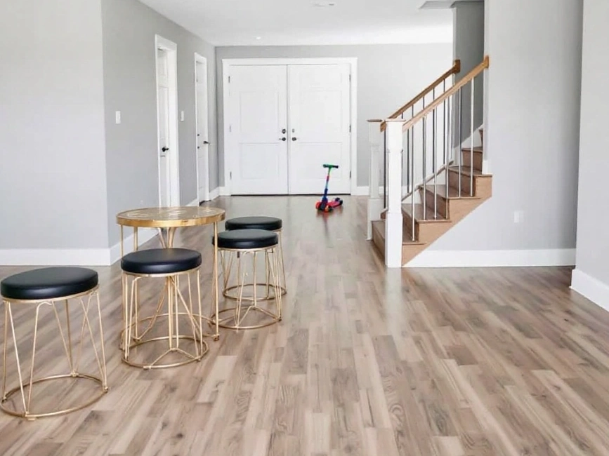a modern remodeled interior with hardwood flooring, stylish gold and black stools, a staircase, and a child's scooter.