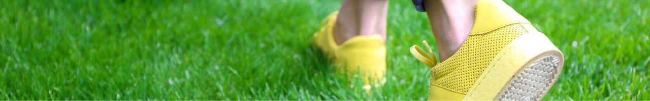 feet walking on the grass with yellow shoes