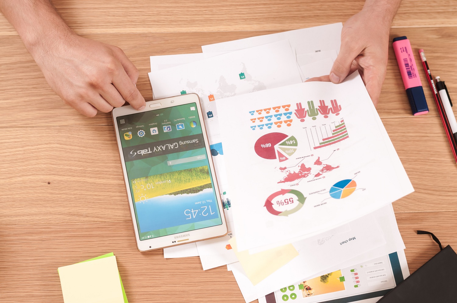 galaxy tablet and pie charts on paper on desk