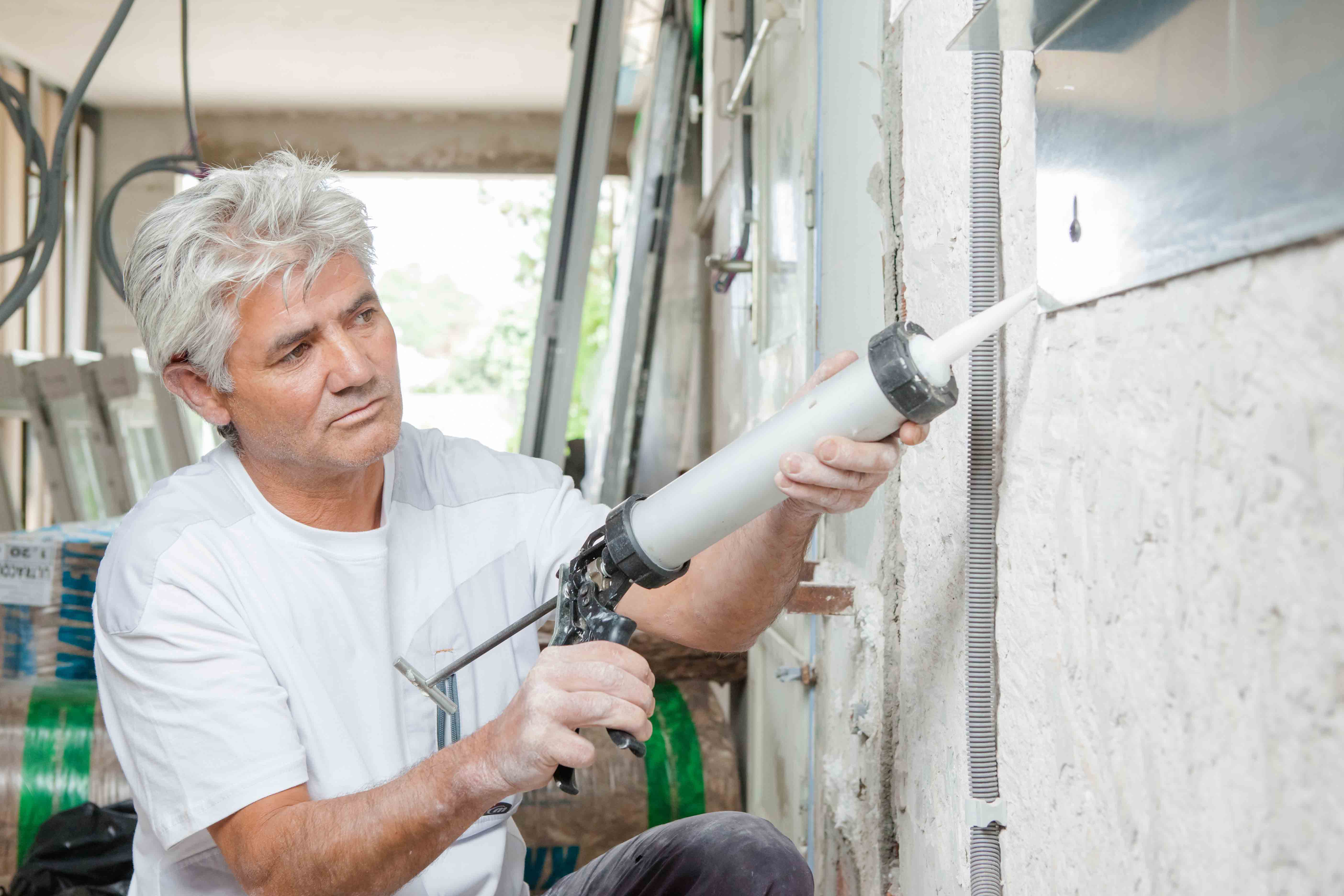 Man using sealant paste in a wall.