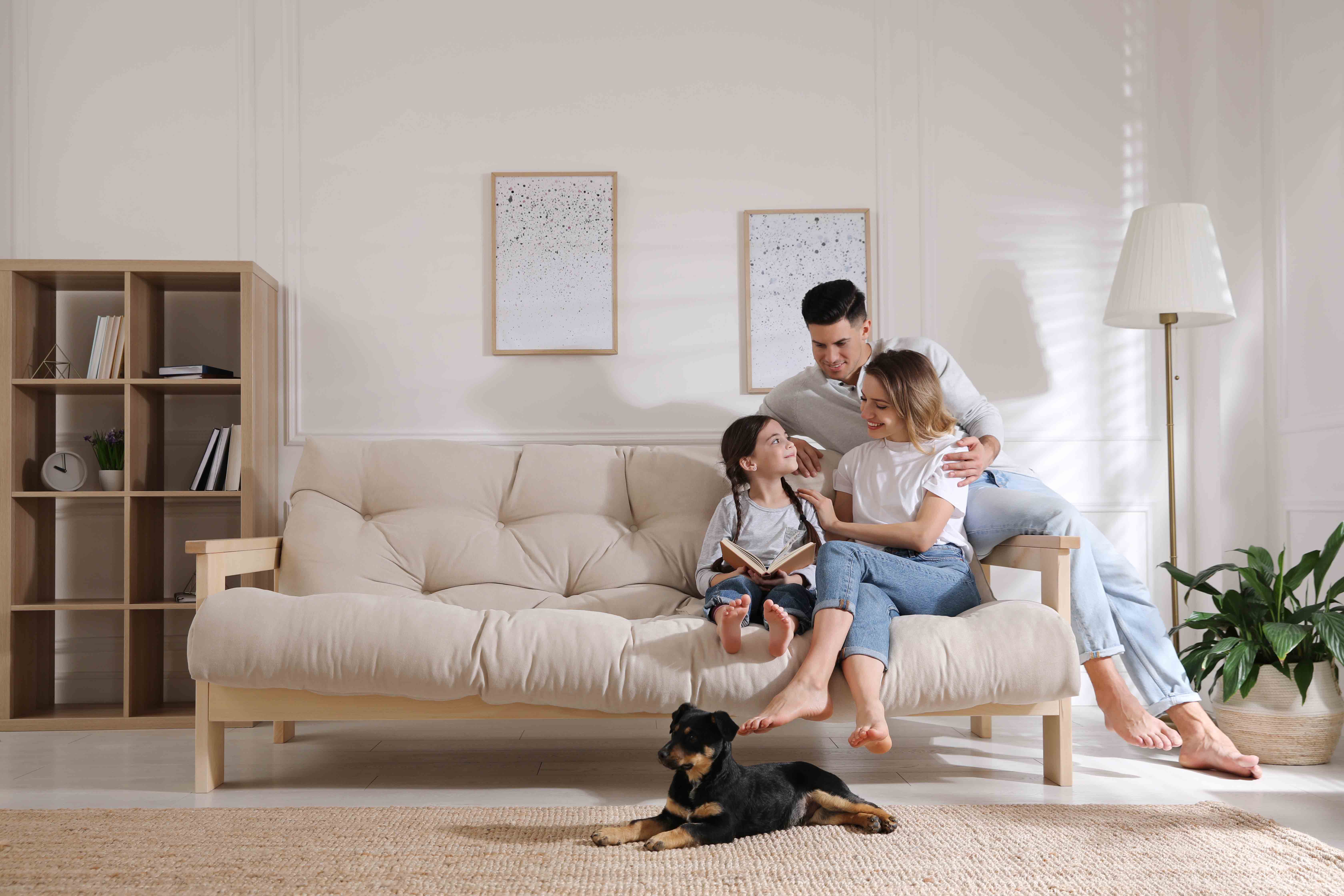 A family sitting on a couch with a dog.