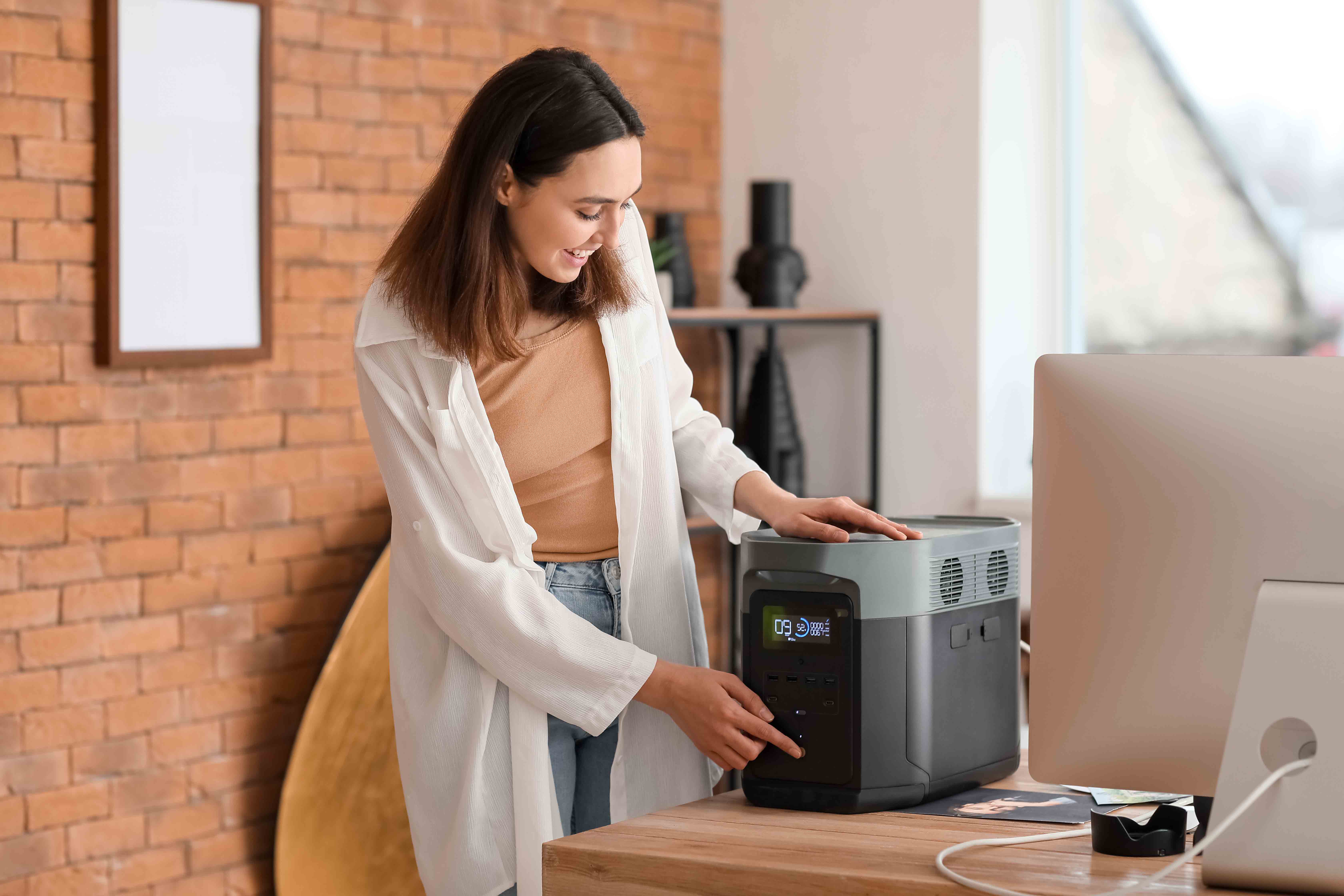 Female with power bank standing by computer.