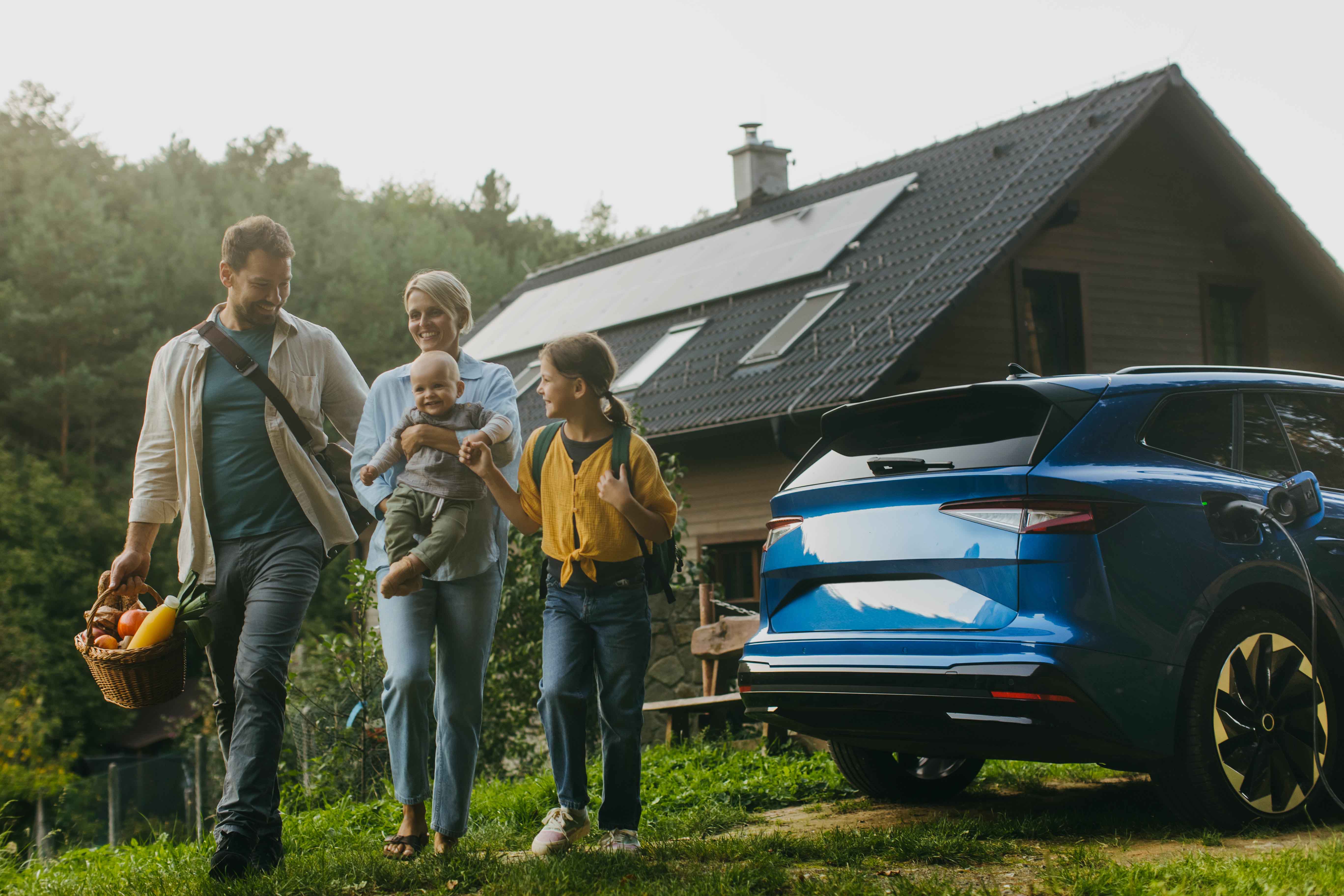 A happy family with children standing in front of their house next to a car.