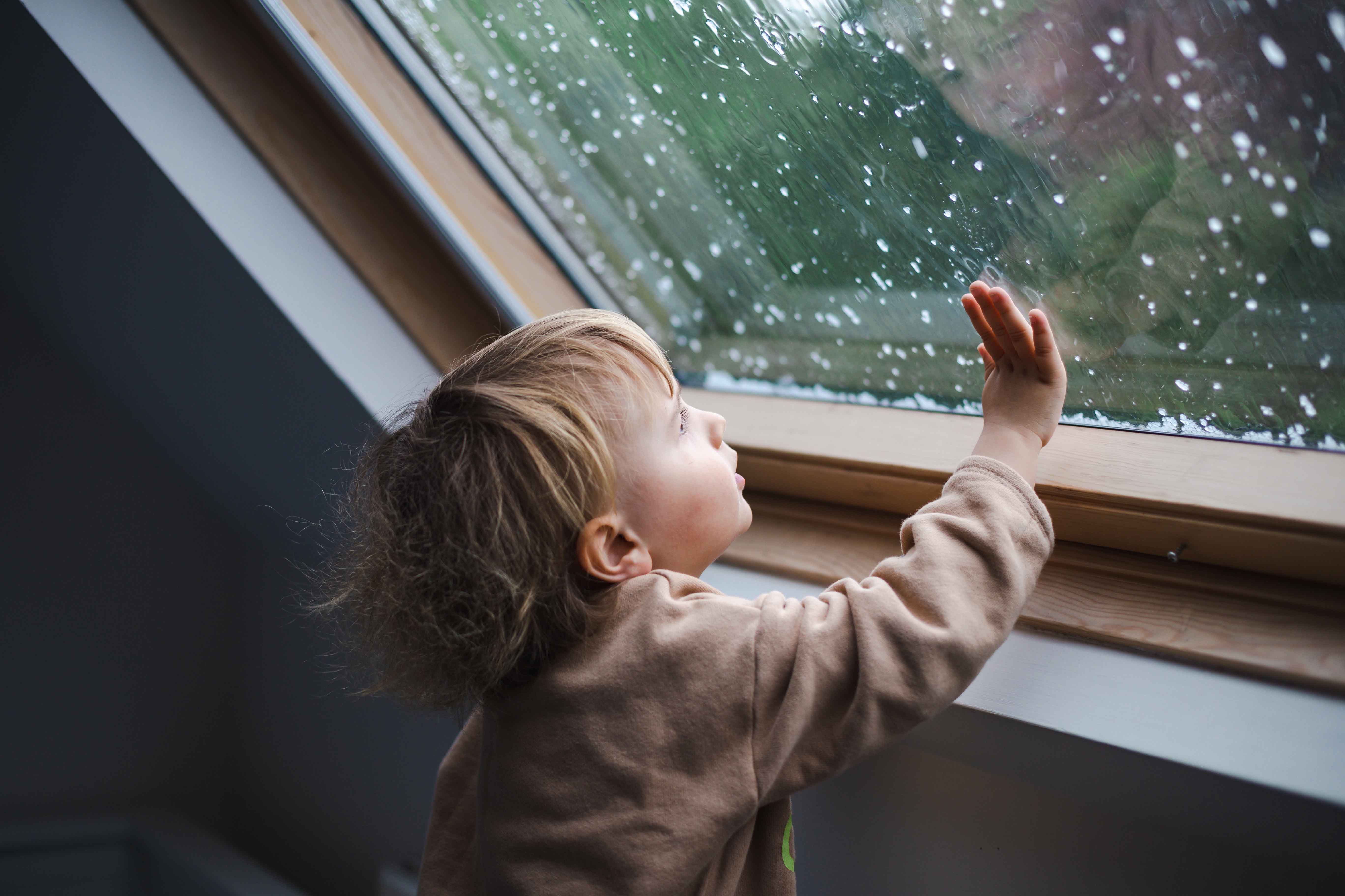A child gazing out a rainy window.