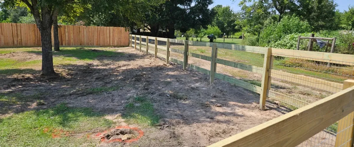 Wood and wire fence installation enclosing backyard with green landscape Wood and wire fence installation enclosing backyard with green landscape