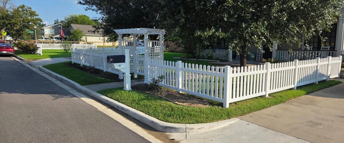 White picket fence enclosing a corner lot front yard with a gate and arbor. White picket fence enclosing a corner lot front yard with a gate and arbor.