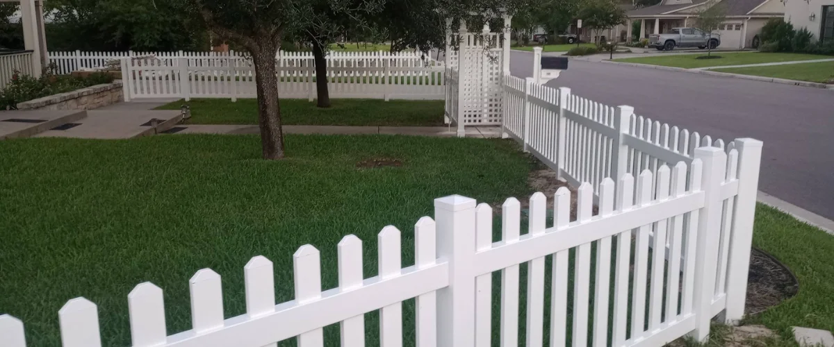 Suburban backyard bordered by white picket fence