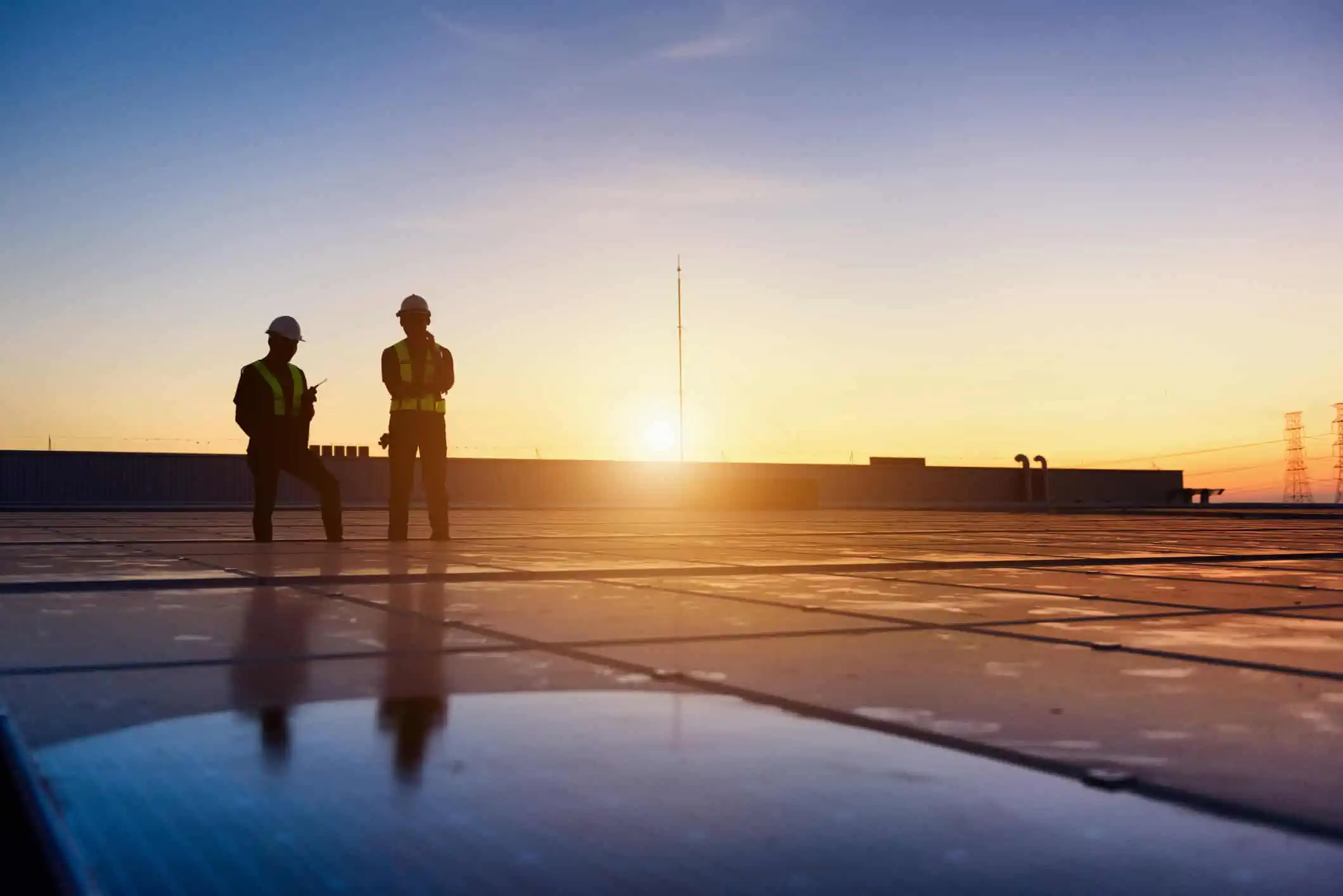 a group of men in safety vests standing on a roof