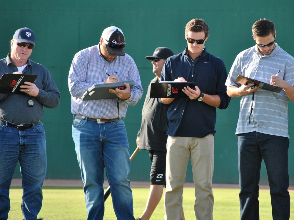 College coaches evaluating high school talent at a recruiting event 