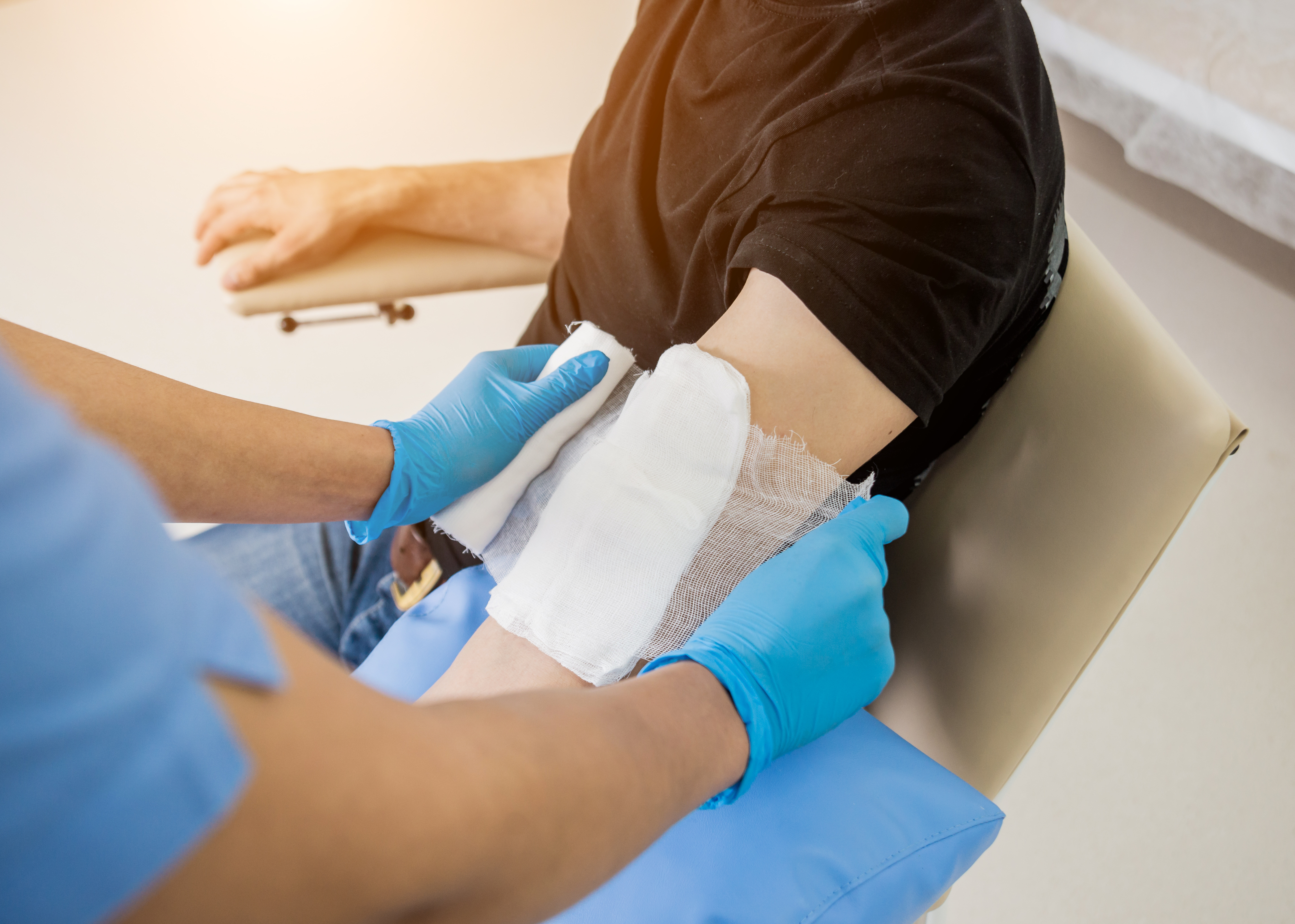 Healthcare professional applying sterile dressing to a patient’s arm wound at Royal Wound Care clinic – expert treatment for acute and chronic injuries. Healthcare professional applying sterile dressing to a patient’s arm wound at Royal Wound Care clinic – expert treatment for acute and chronic injuries.