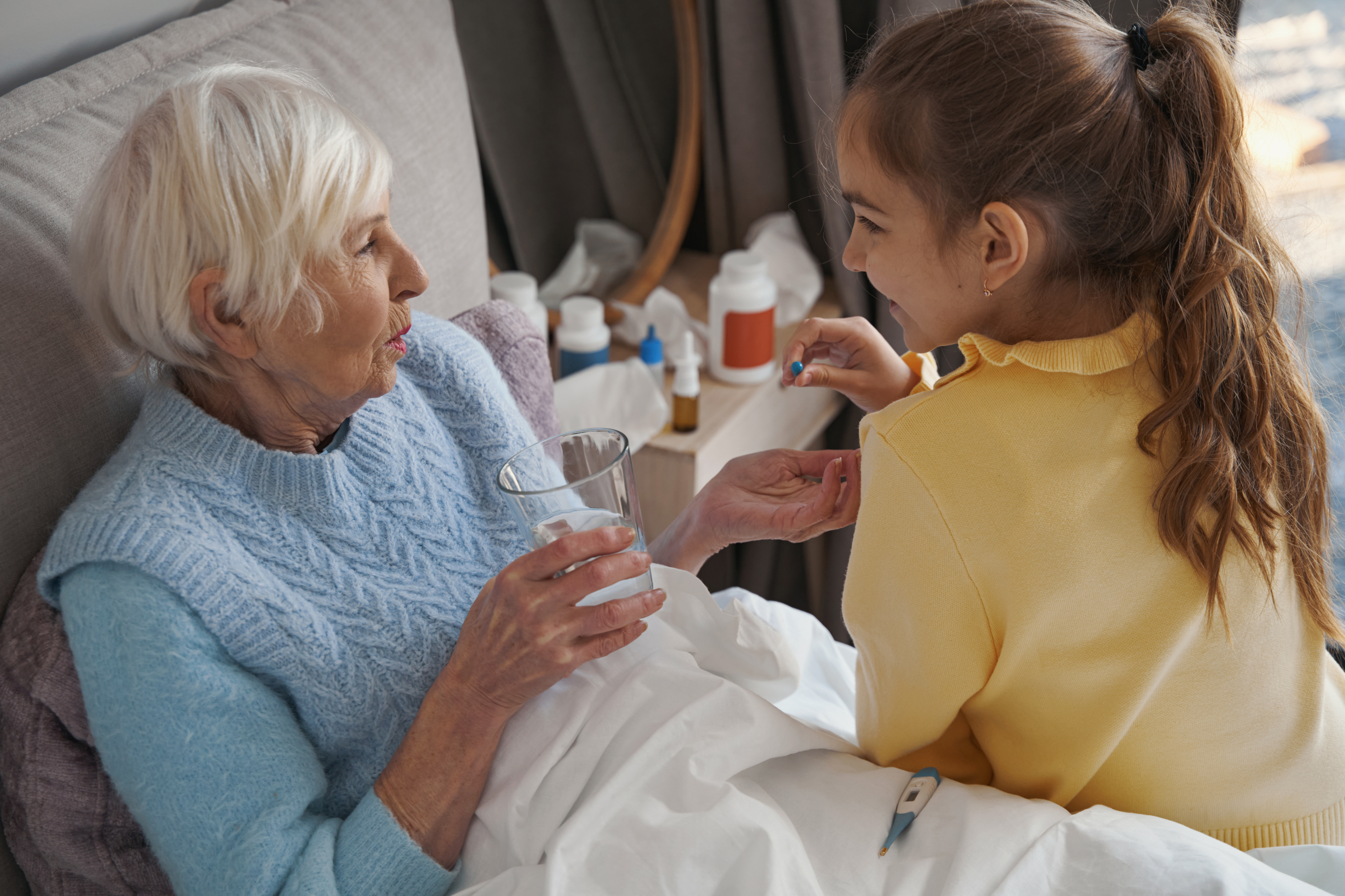 Royal Wound Care home caregiver helping an elderly woman take medication while resting in bed. Royal Wound Care home caregiver helping an elderly woman take medication while resting in bed.
