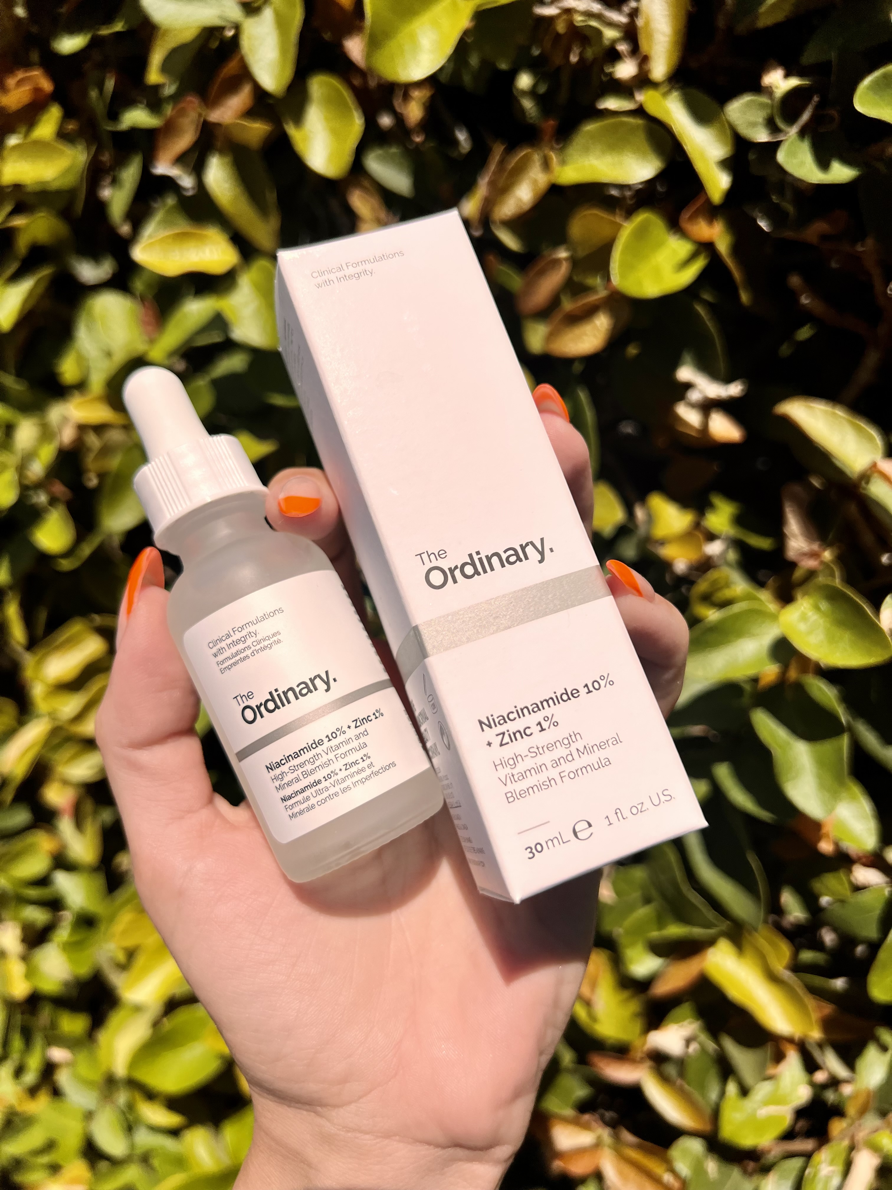 Close up shot of a woman's hand holding 'The Ordinary' Niacinamide Serum .