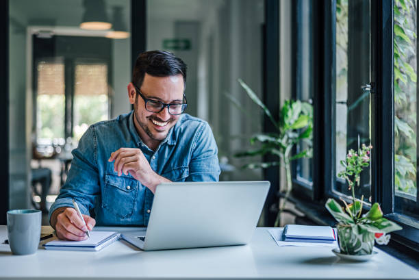  An insurance agent working at their office desk with plants near monitor.