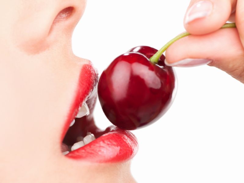 alt: image of woman putting a cherry into her mouth