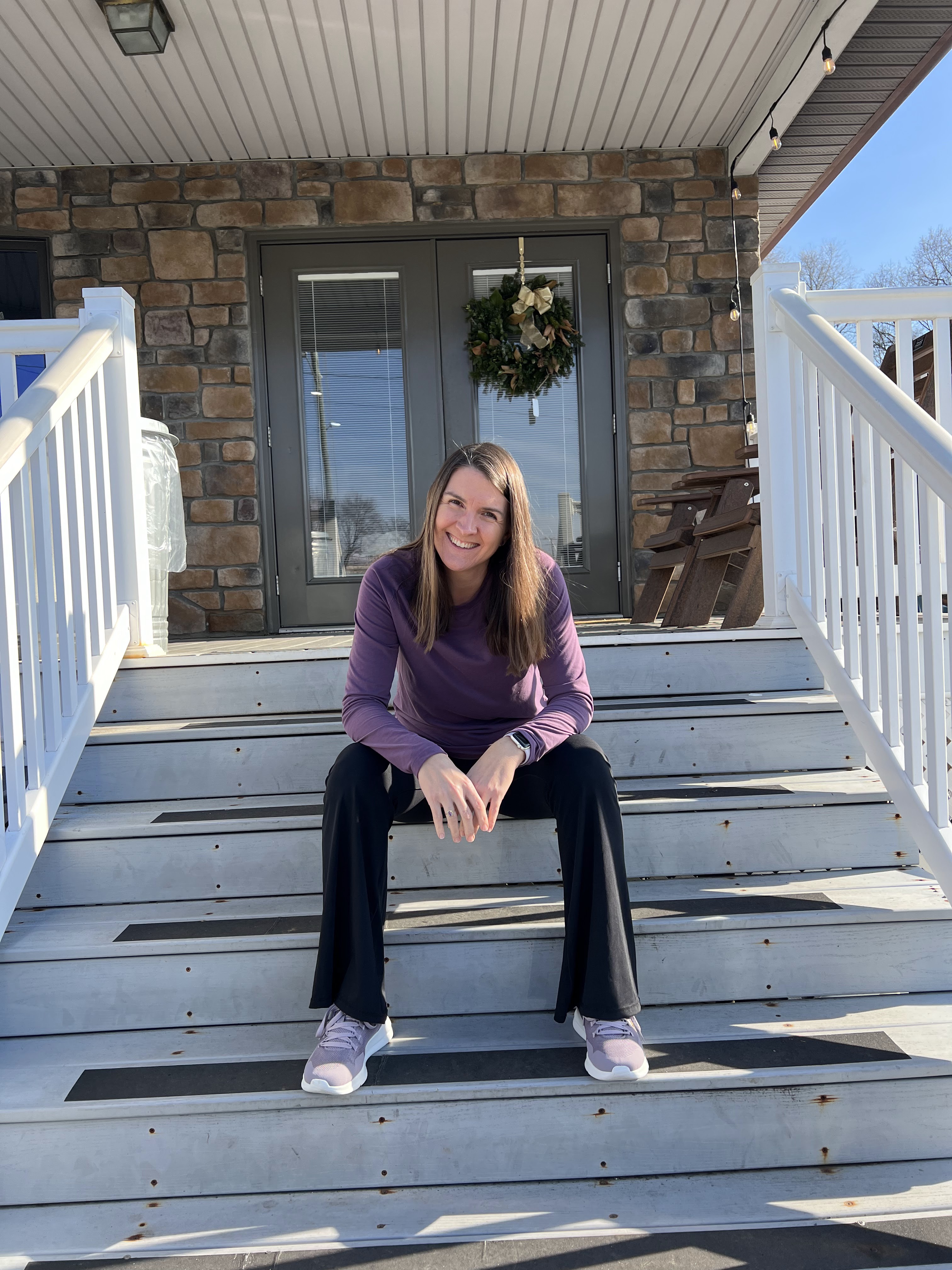 Coach and Personal Trainer Mary Louise Rose sitting on a staircase wearing athletic clothes.