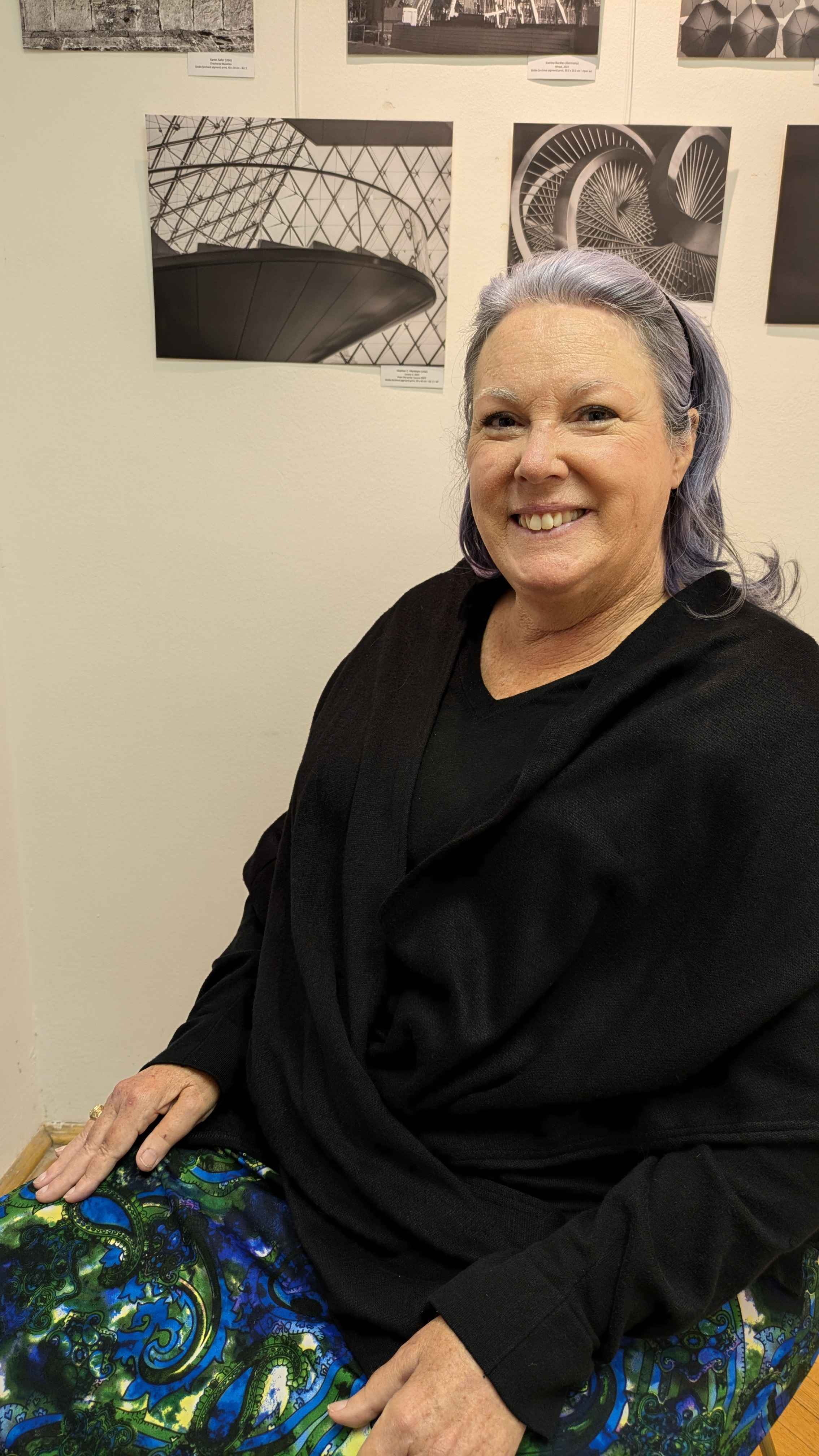 Heather sitting by one of her photos in a gallery