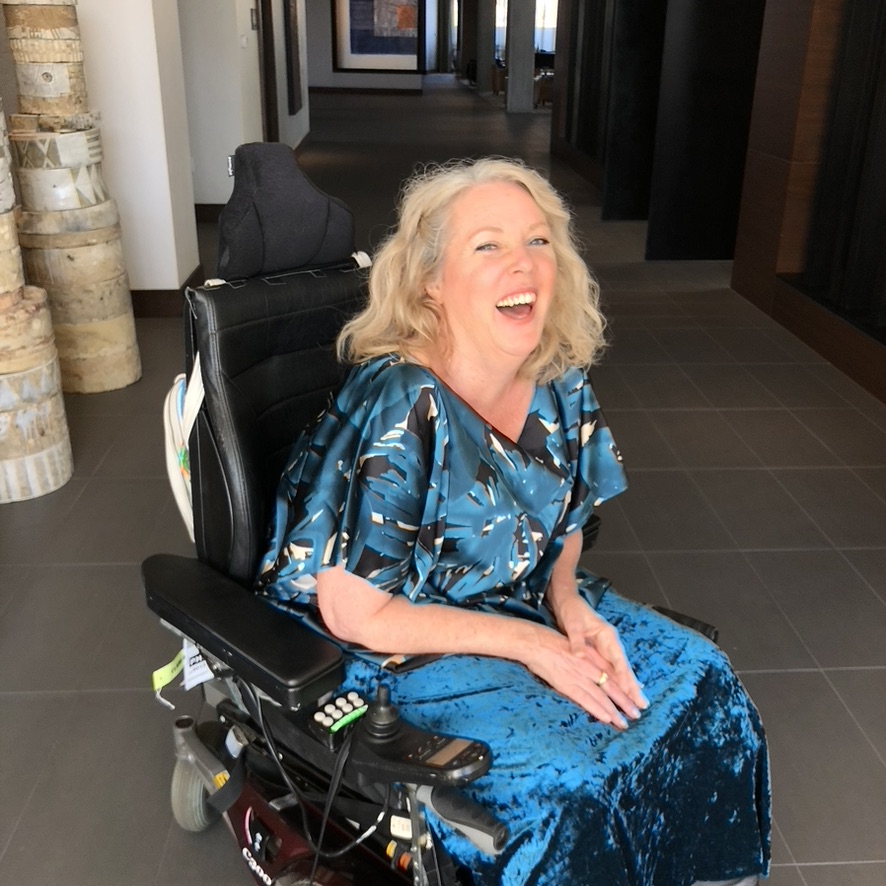 Heather sitting on her power wheelchair laughing