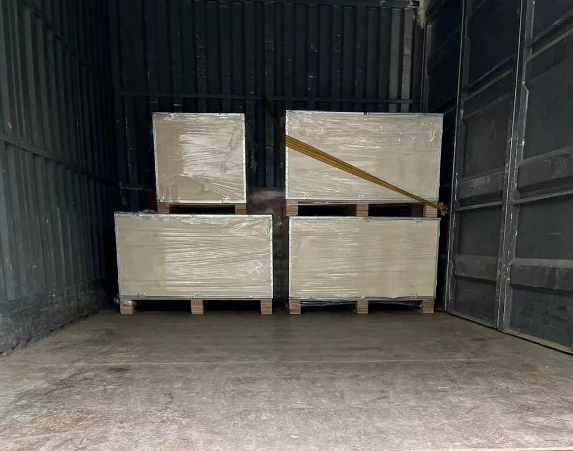 Four crates, each containing components for a YOLO-202in TV project, are securely loaded onto the back of a delivery truck, destined for Long Beach, CA, and awaiting transportation to their final destination.