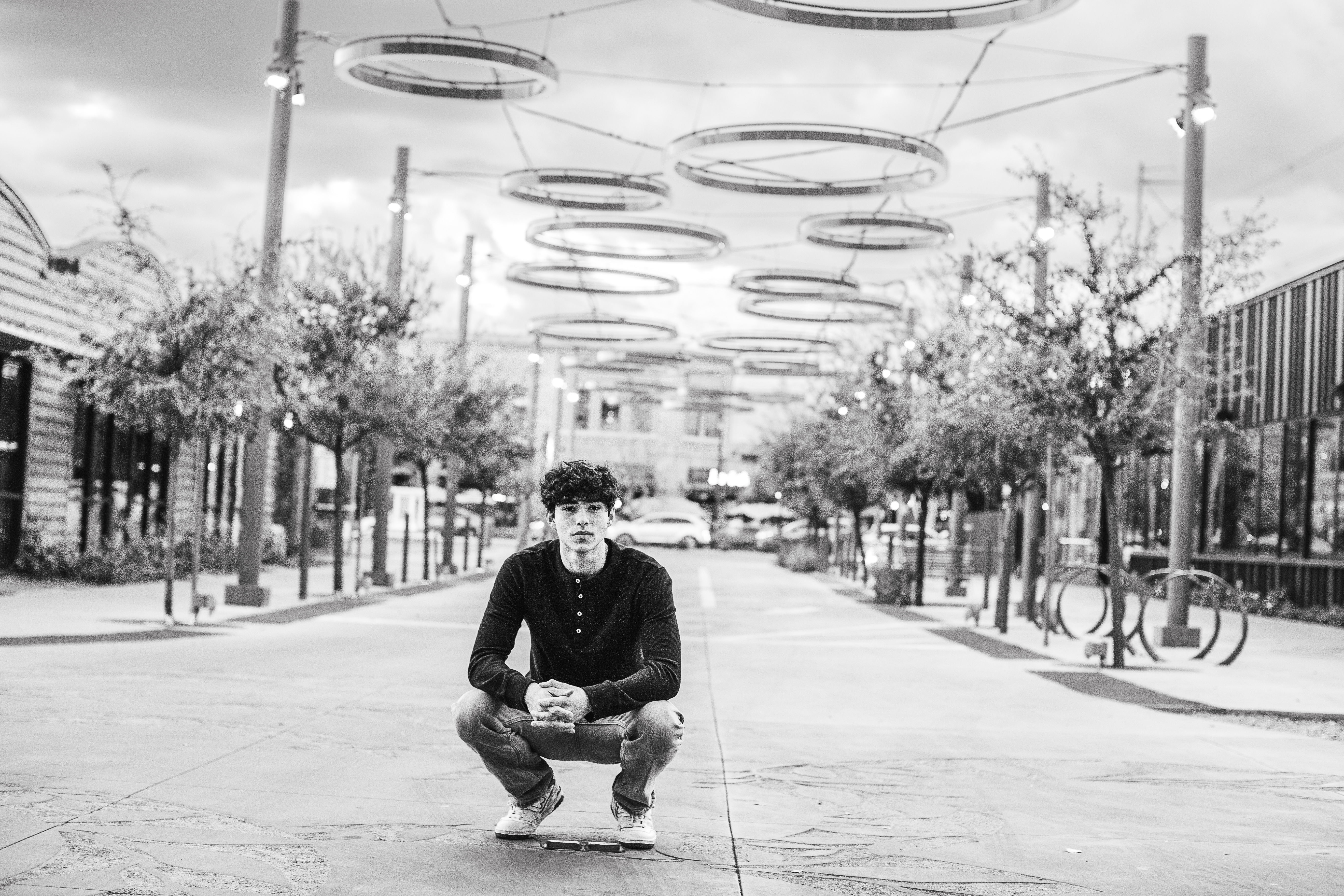 Black and white portrait of a senior boy under string lights in Downtown Gilbert, Arizona, captured by Andria May Photography. Black and white portrait of a senior boy under string lights in Downtown Gilbert, Arizona, captured by Andria May Photography.