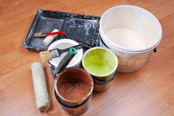 aint cans, brushes, rollers, and tray set up on a hardwood floor aint cans, brushes, rollers, and tray set up on a hardwood floor