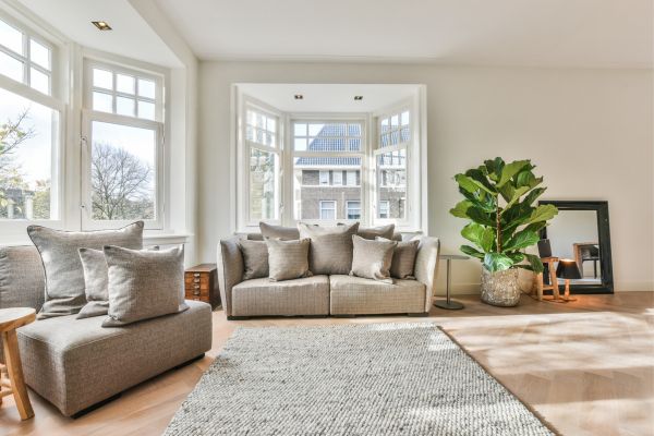 Modern living room with large windows, neutral sofas, and a cozy rug. Modern living room with large windows, neutral sofas, and a cozy rug.