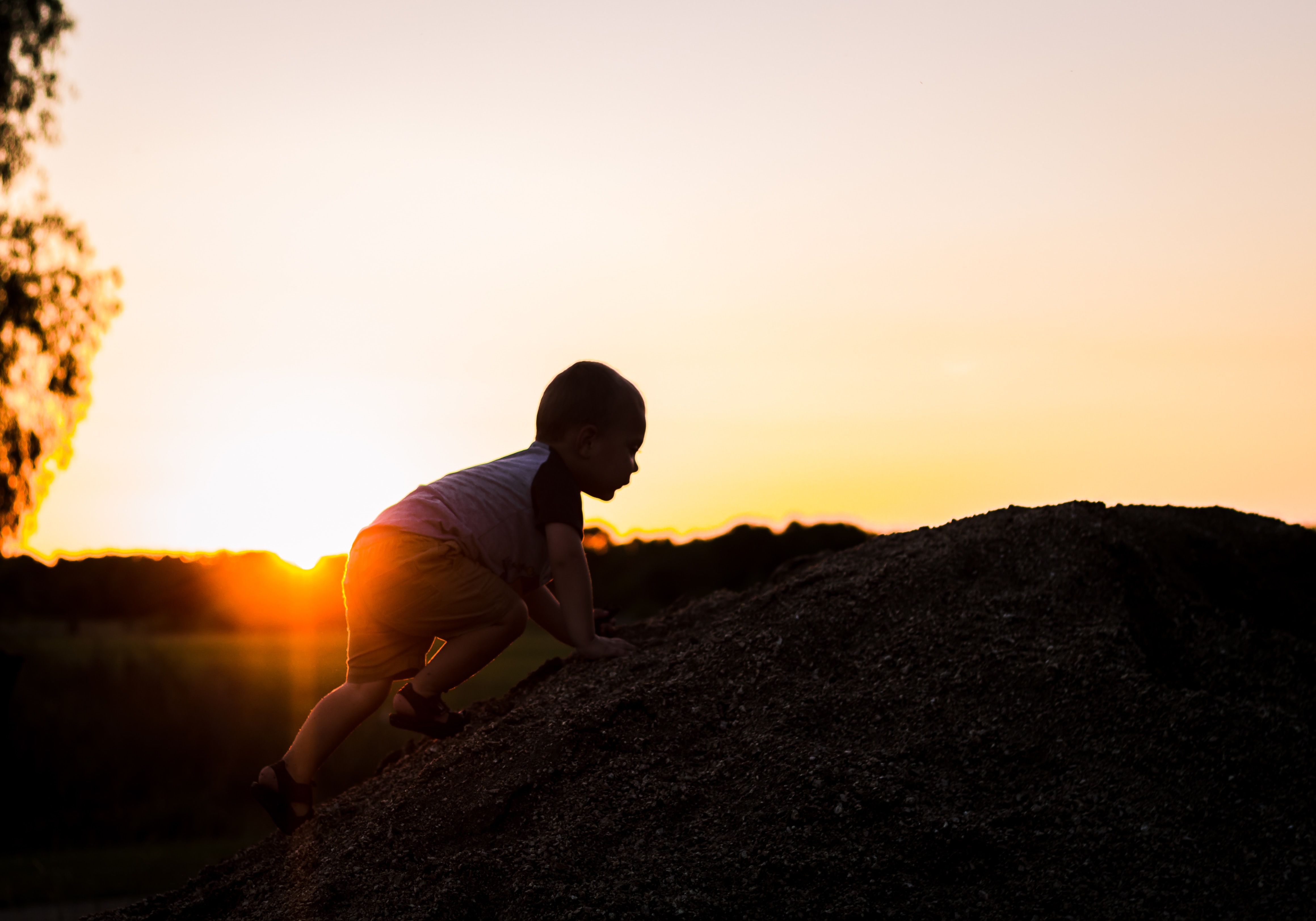 Image of a baby climbing upwards against the sun, depicting them taking steps and hitting milestones