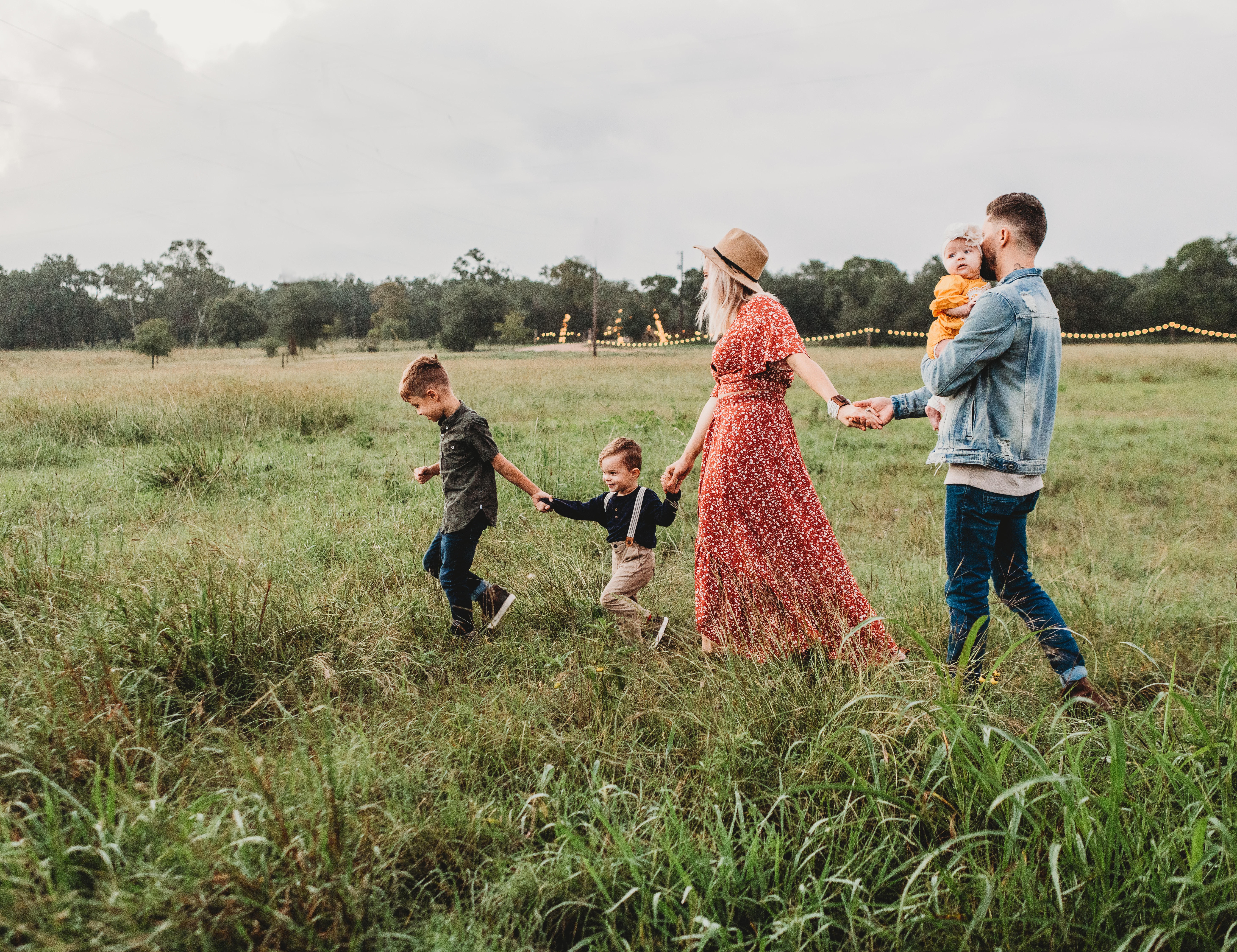 Image of a family with little children, holding hands, walking through a meadow, depicting a family enjoying their time together outdoors