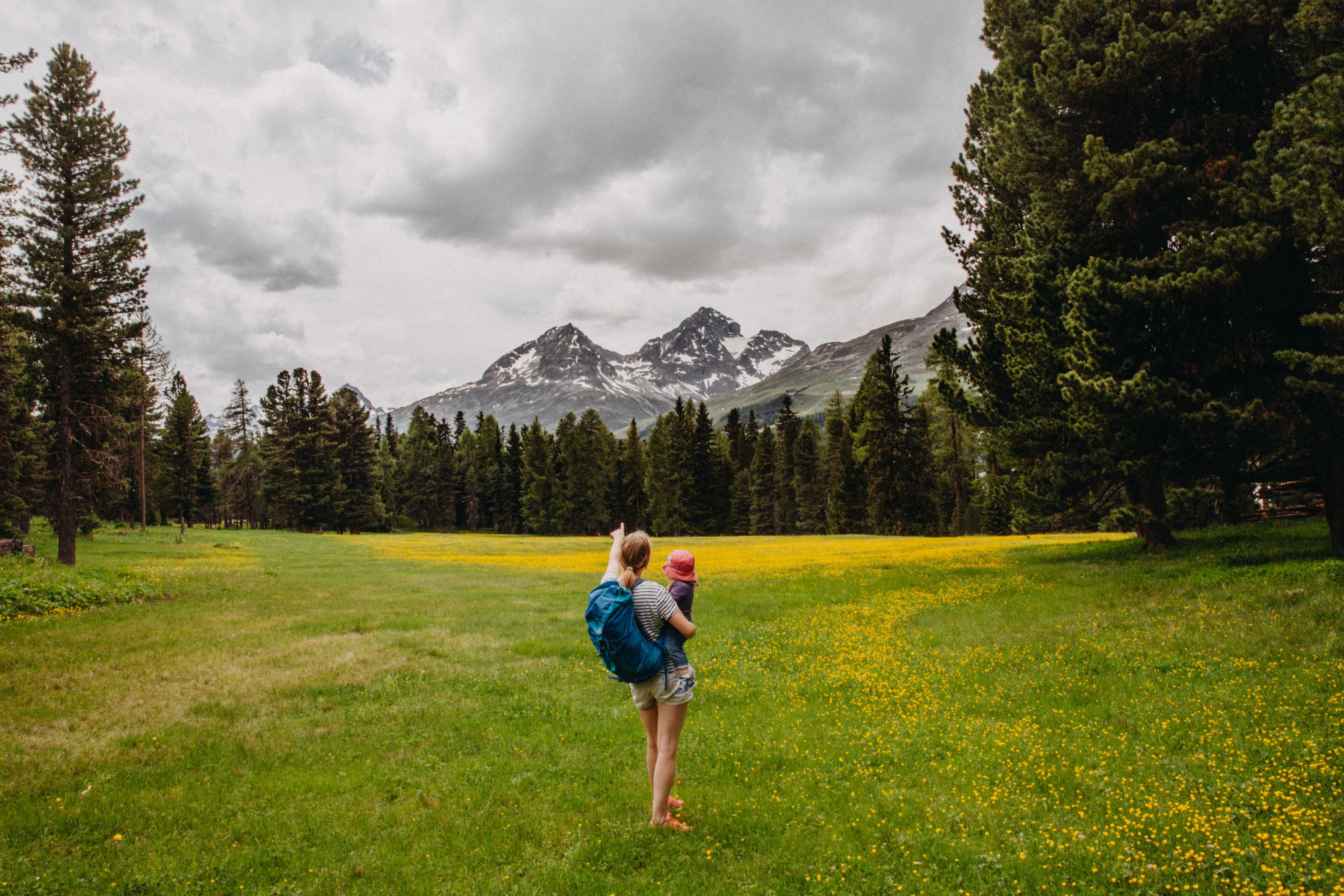 Image of a woman on a hike with a child, pointing away towards a mountain