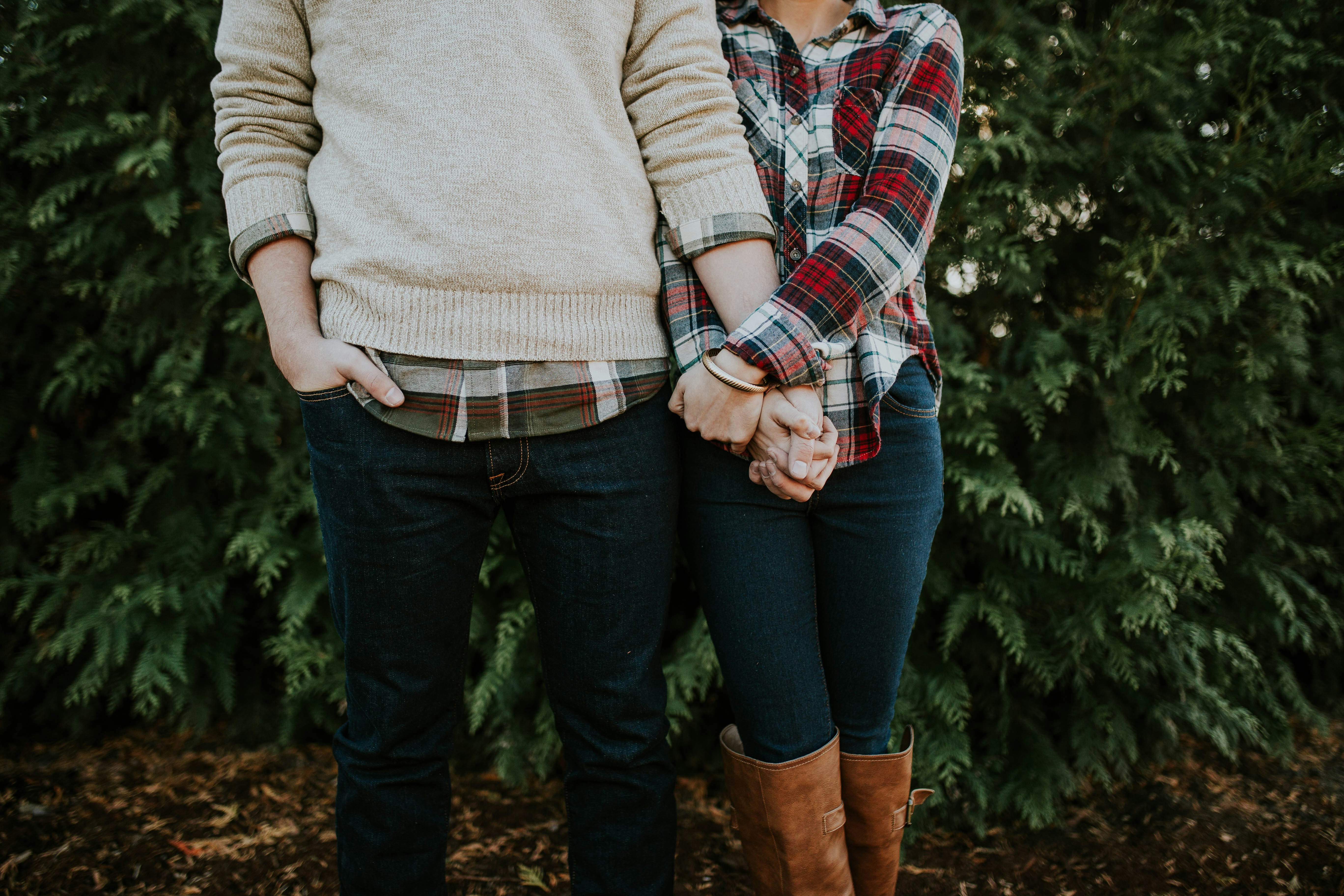 Image of a couple's legs only, standing next to each other, in front of ferns in the woods