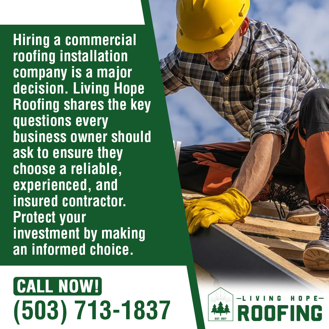 Roofer in yellow hard hat installing a dark roofing material on a commercial flat roof section. 