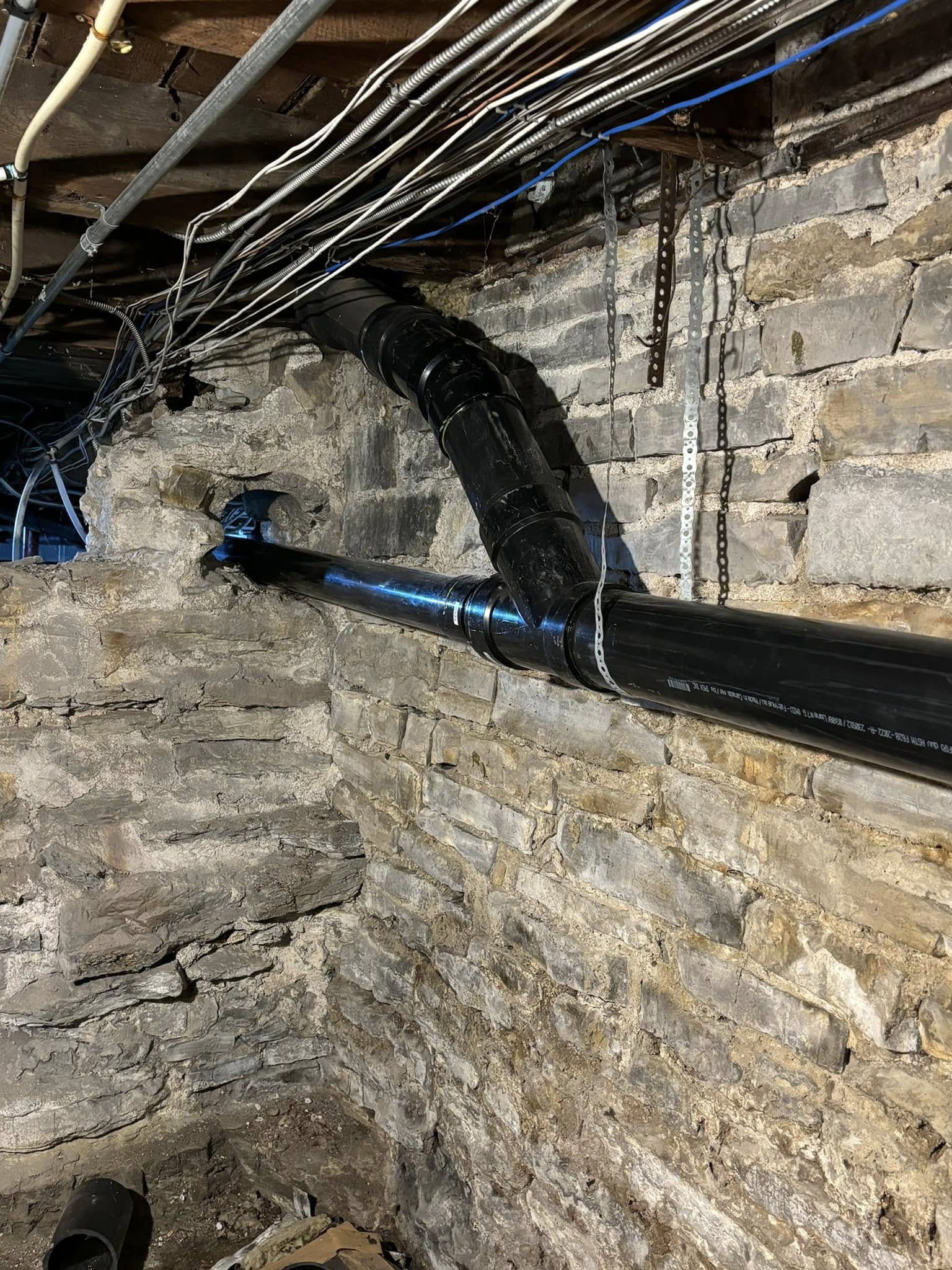 New pipe installed along a stone foundation wall