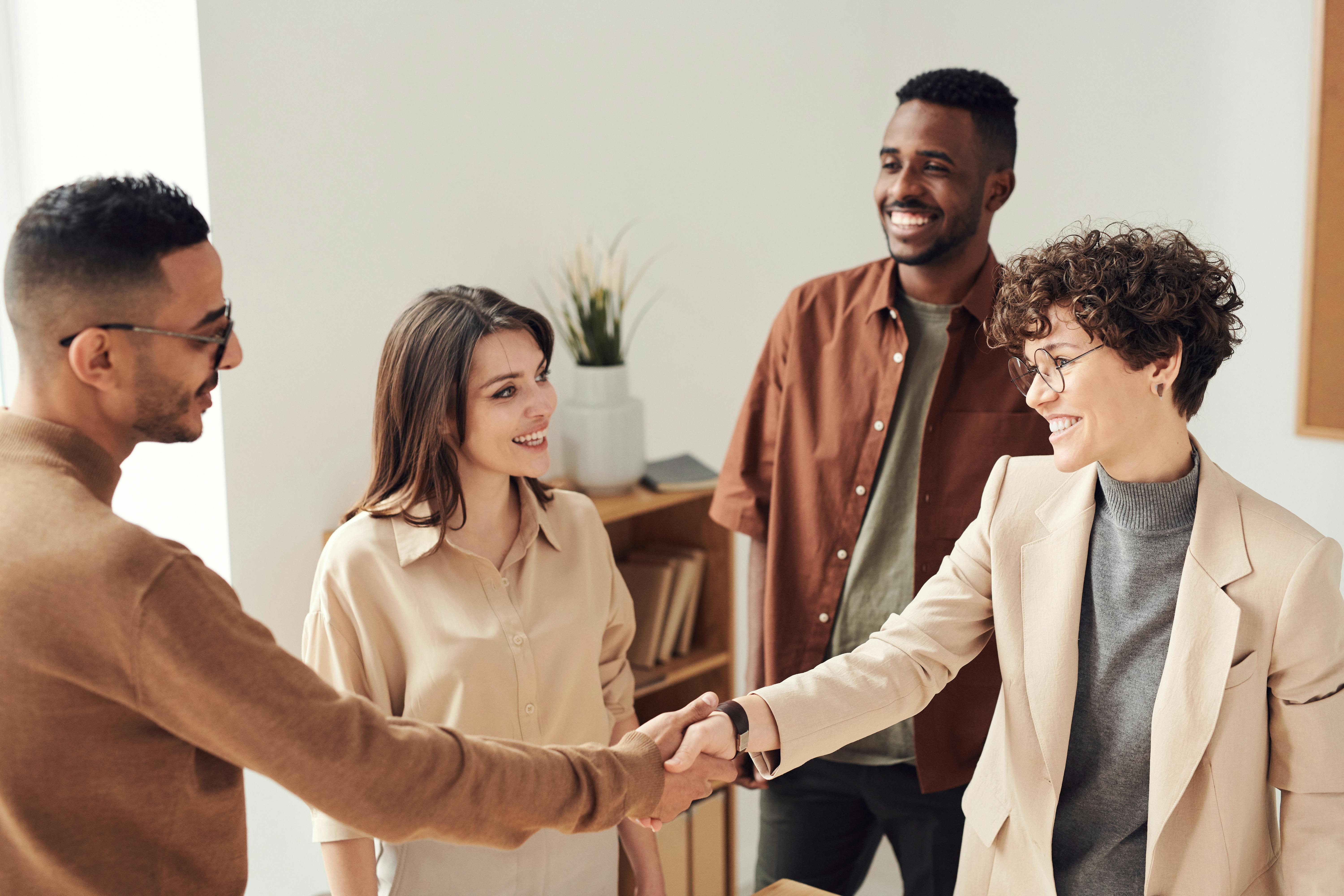 A diverse group of professionals shaking hands in a modern office setting, symbolizing collaboration and agreement. A diverse group of professionals shaking hands in a modern office setting, symbolizing collaboration and agreement.