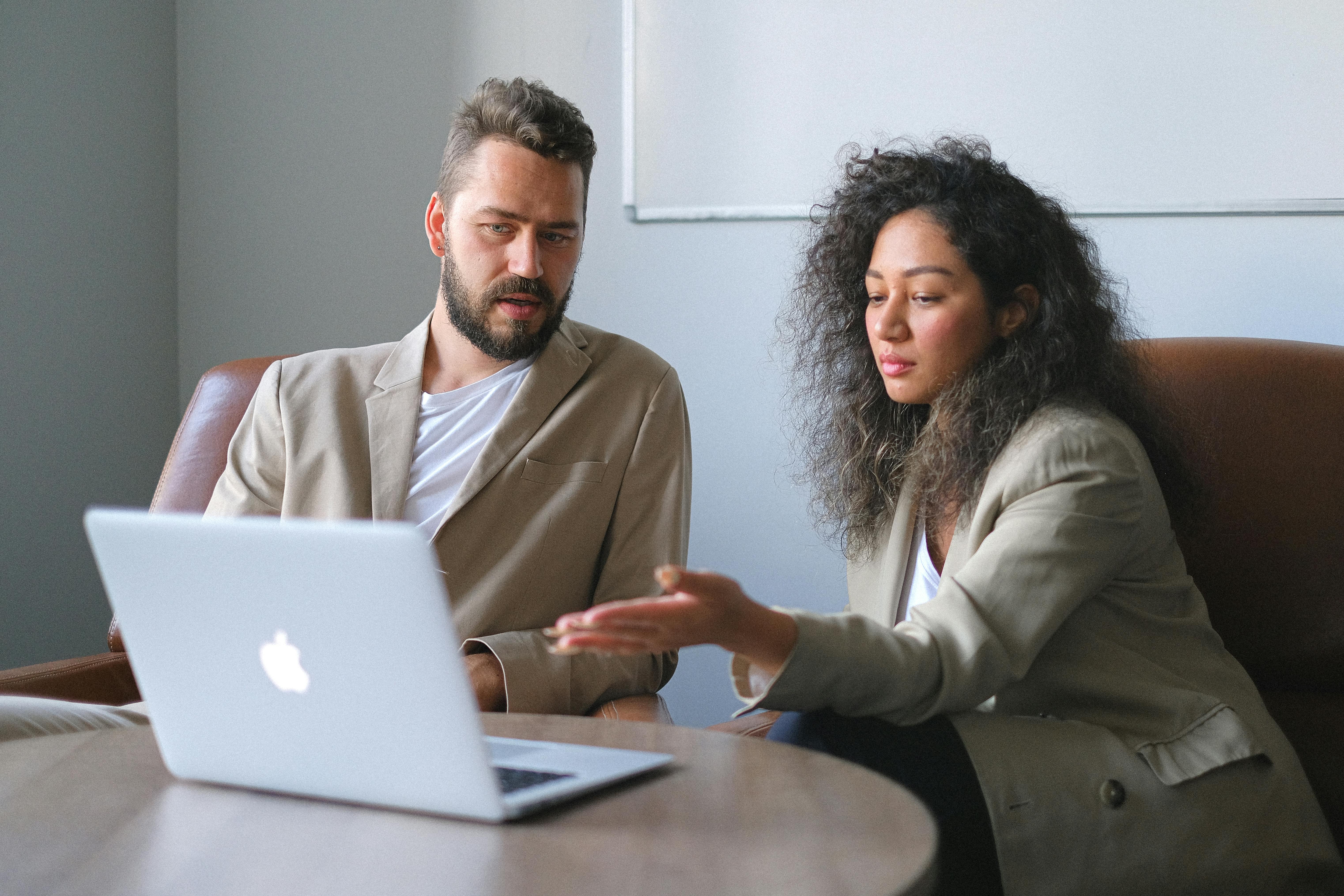 A man and woman sitting at a table, collaborating on a laptop, with a focused and interactive atmosphere. A man and woman sitting at a table, collaborating on a laptop, with a focused and interactive atmosphere.
