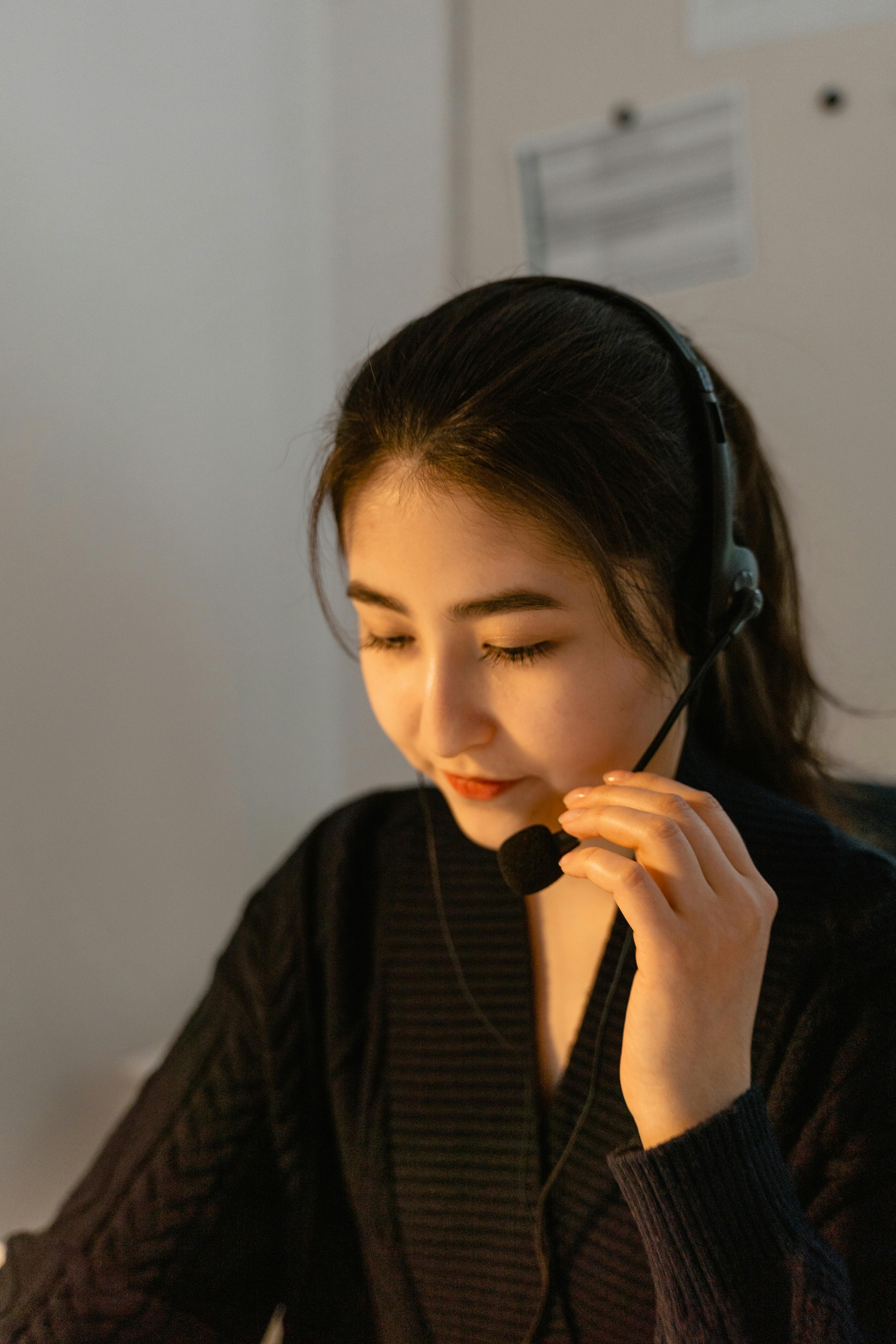 A woman wearing a headset, engaged in a conversation on the phone, focused and attentive. A woman wearing a headset, engaged in a conversation on the phone, focused and attentive.