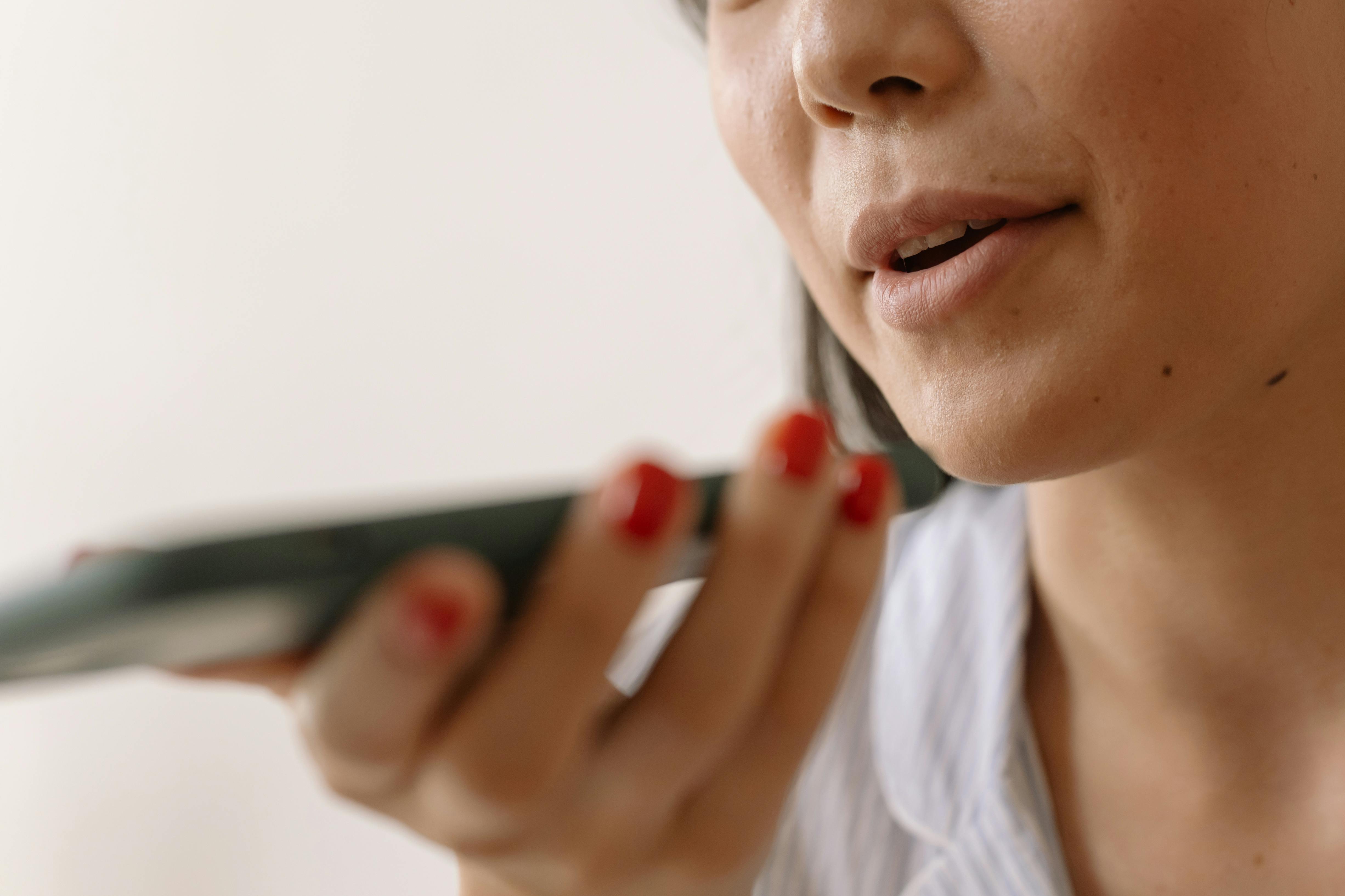 A woman with a serious expression holds a cell phone to her mouth, as if engaged in an important conversation. A woman with a serious expression holds a cell phone to her mouth, as if engaged in an important conversation.