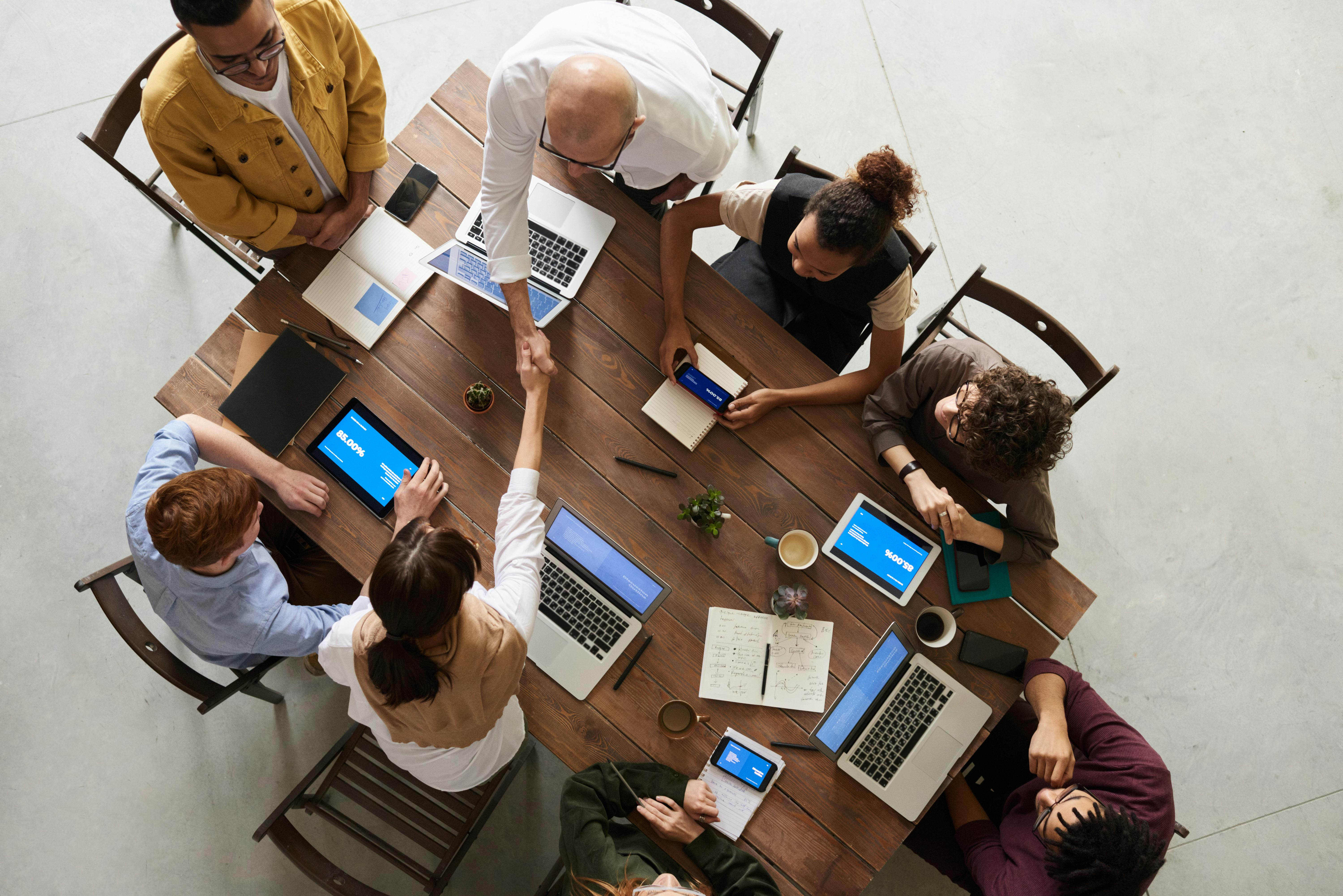 A diverse group of people collaborating around a table, each focused on their laptops, engaged in discussion and teamwork. A diverse group of people collaborating around a table, each focused on their laptops, engaged in discussion and teamwork.