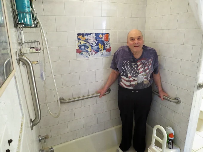 A professional installing a grab bar in a shower for a client.