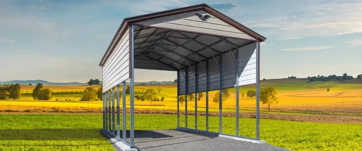 Open metal carport with partial siding set against a scenic farmland backdrop