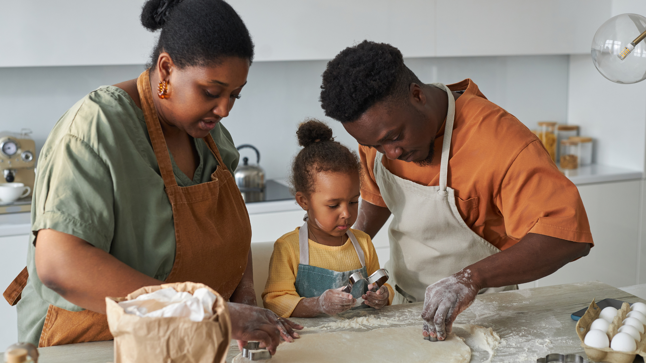 Joyful Black toddler with flour-covered hands and face, learning to use a cookie cutter with her parents. Her dad guides her while her mom cuts dough, showcasing a loving co-parenting moment. A heartwarming scene of teamwork and family bonding after divorce. Joyful Black toddler with flour-covered hands and face, learning to use a cookie cutter with her parents. Her dad guides her while her mom cuts dough, showcasing a loving co-parenting moment. A heartwarming scene of teamwork and family bonding after divorce.