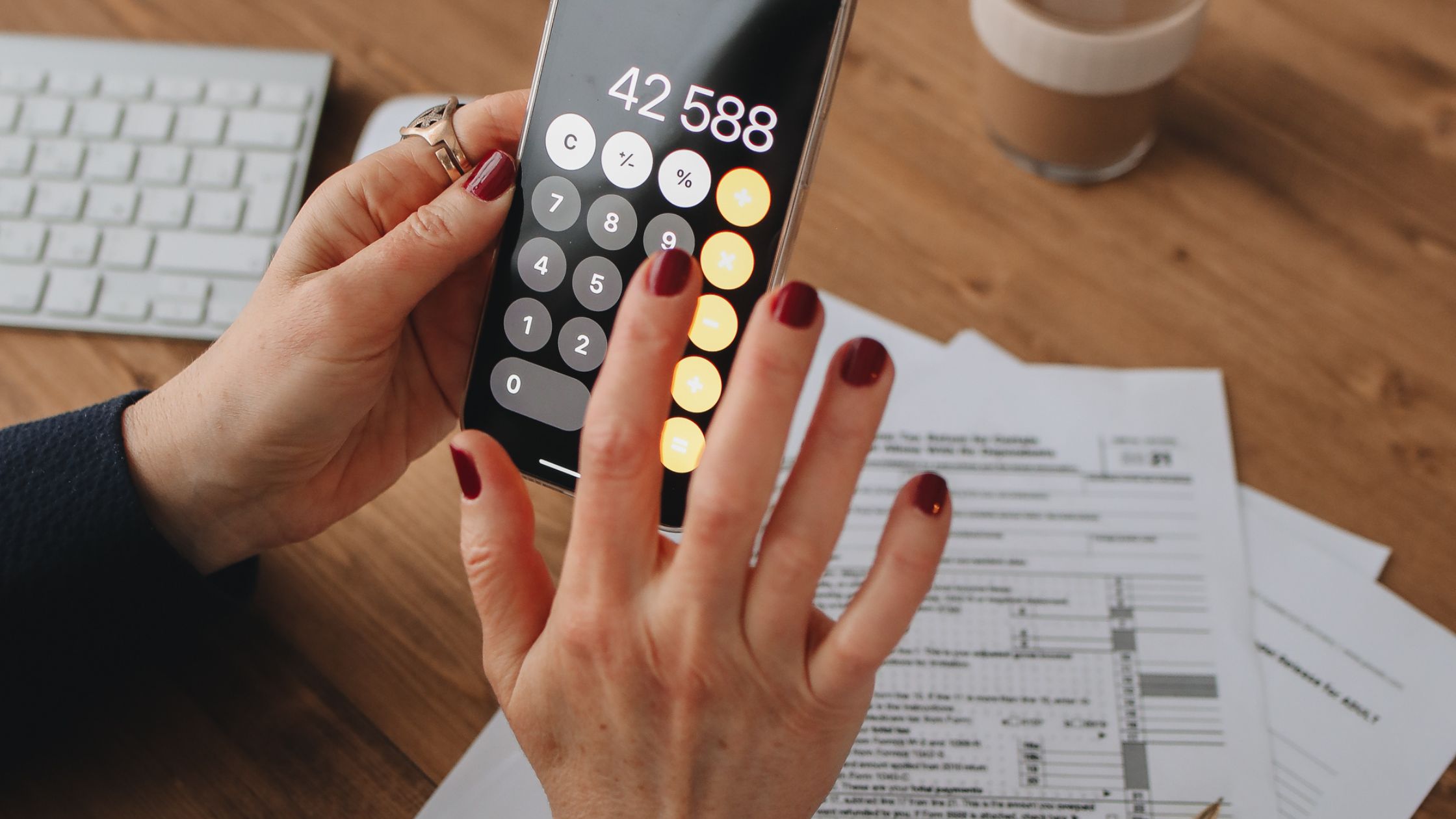 "Close-up of a woman's hands with a ring using a calculator, with financial documents spread out on the table in the background — representing asset review during a high-net-worth divorce. "Close-up of a woman's hands with a ring using a calculator, with financial documents spread out on the table in the background — representing asset review during a high-net-worth divorce.