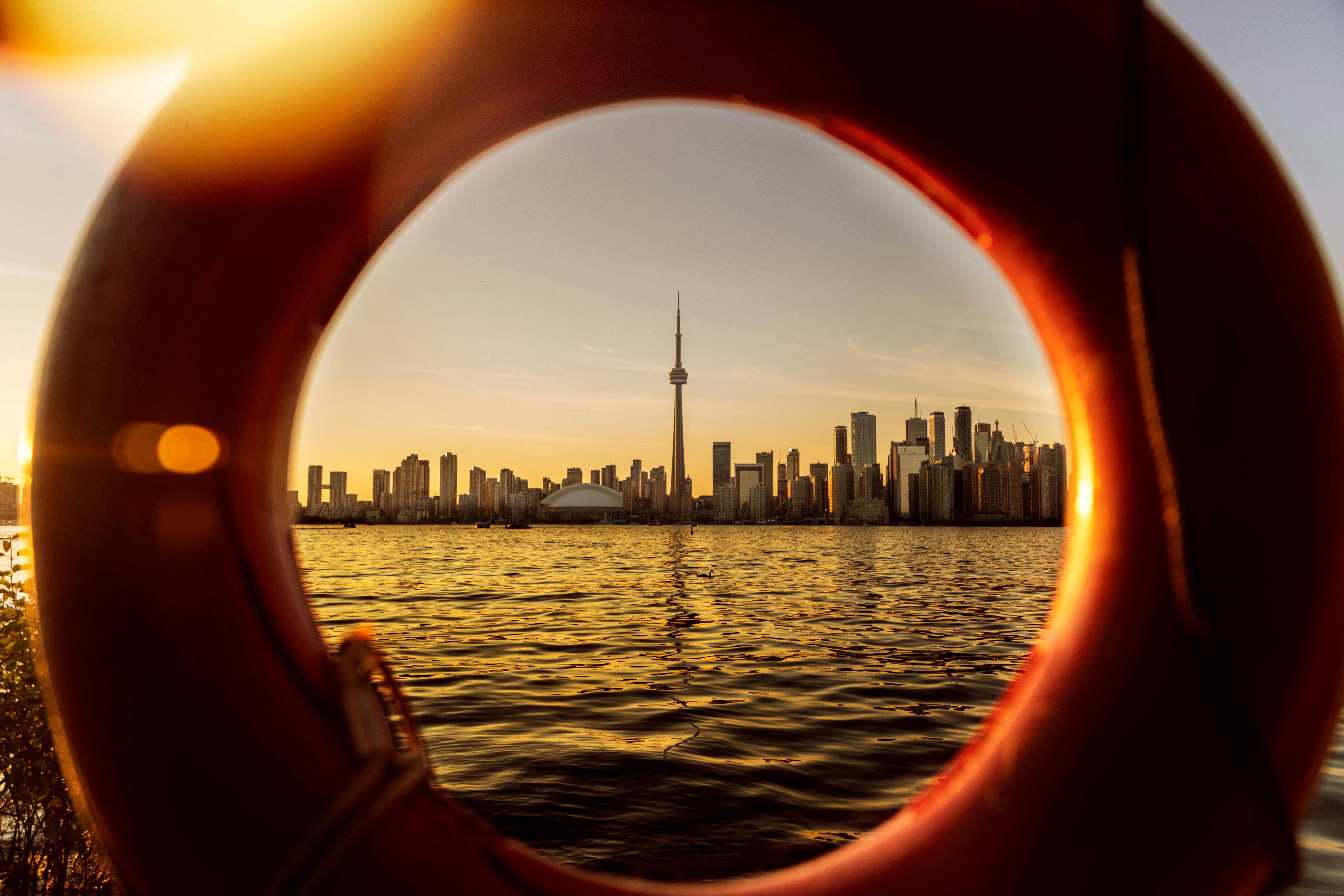 Toronto skyline at sunset with CN Tower framed through a lifebuoy ring from Lake Ontario Toronto skyline at sunset with CN Tower framed through a lifebuoy ring from Lake Ontario