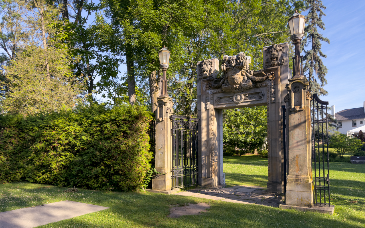 Ornate heritage gate entrance to Guild Park & Gardens Scarborough with decorative stonework, wrought iron gates, and classical lamp posts surrounded by parkland. Image Courtesy: City of Toronto