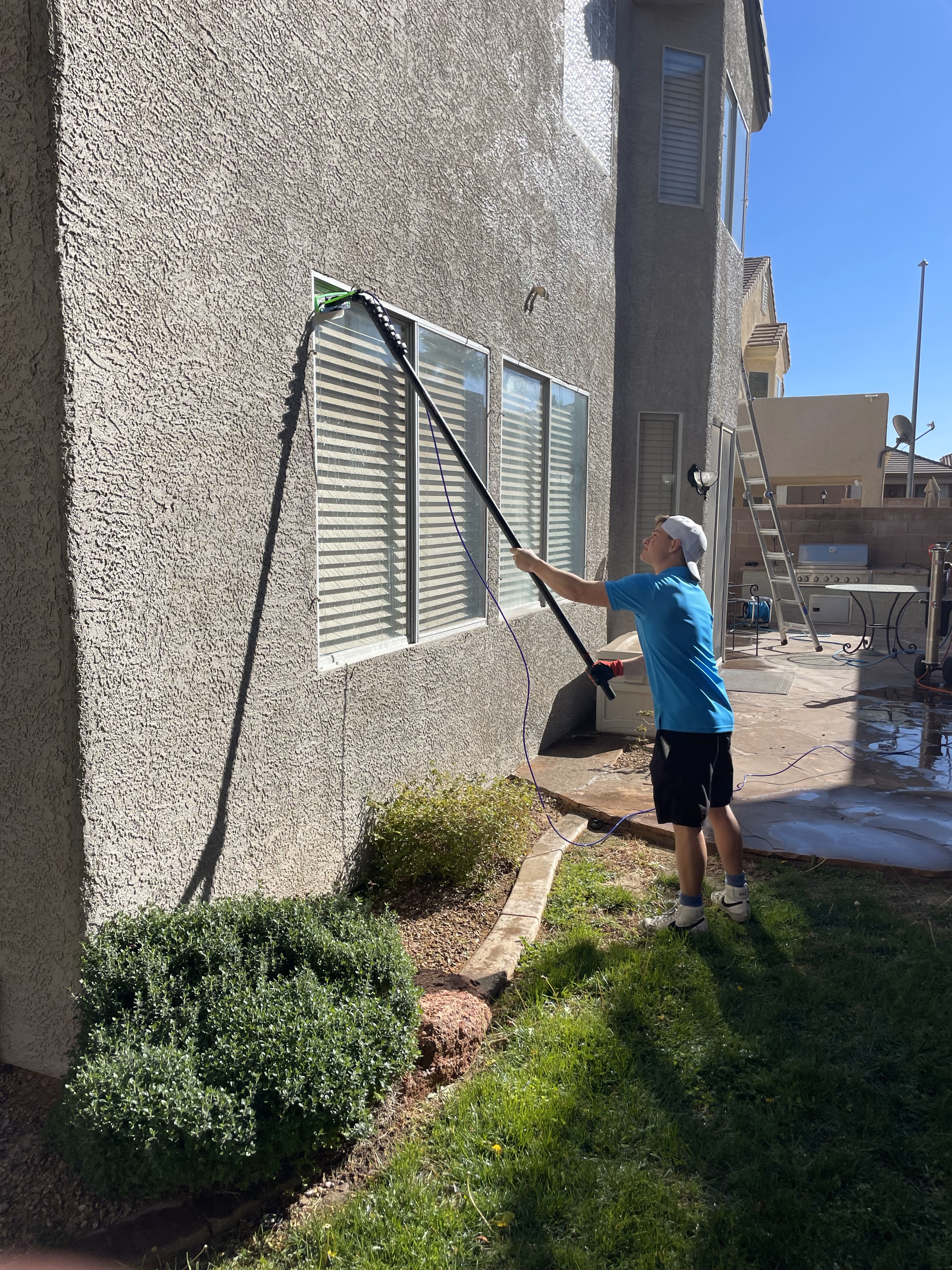 Professional window cleaner using extension pole to clean second-story window in Las Vegas Professional window cleaner using extension pole to clean second-story window in Las Vegas